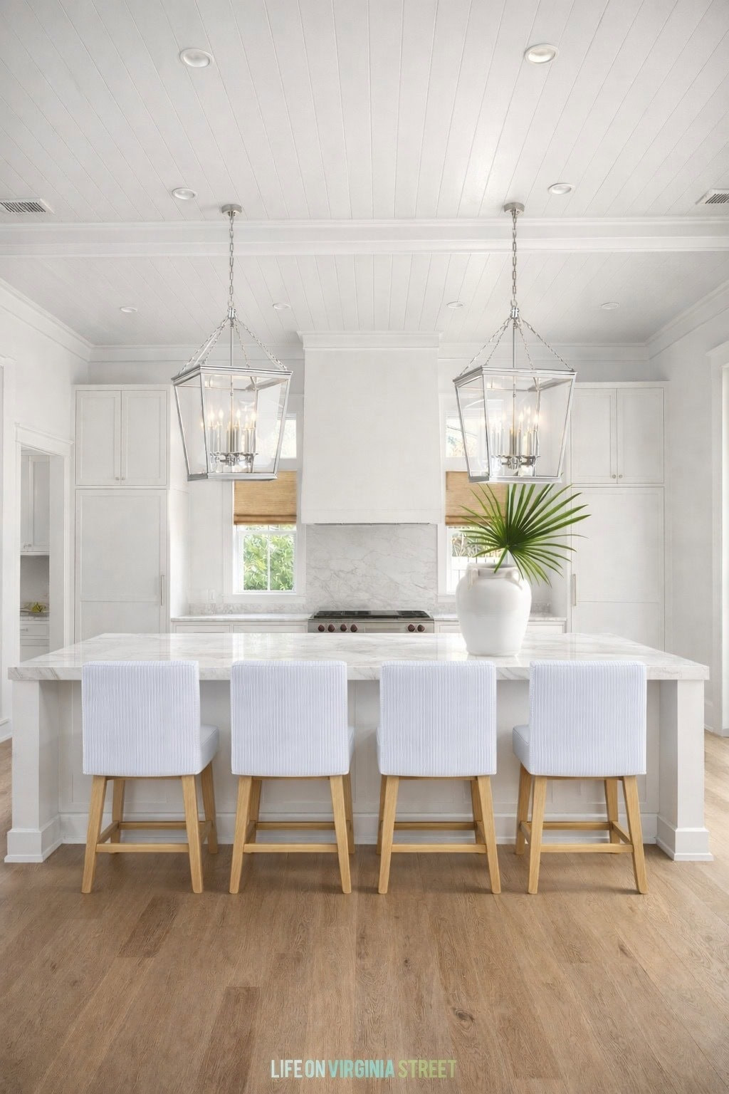 An AI rendering of our kitchen design board featuring blue and white pinstriped counter stools, a blue and cream striped rug, polished nickel chandeliers, striped cafe curtains and more. See the full design here: https://lifeonvirginiastreet.com/classic-coastal-kitchen-design-plans/ 

#LTKSaleAlert #LTKSeasonal #LTKHome