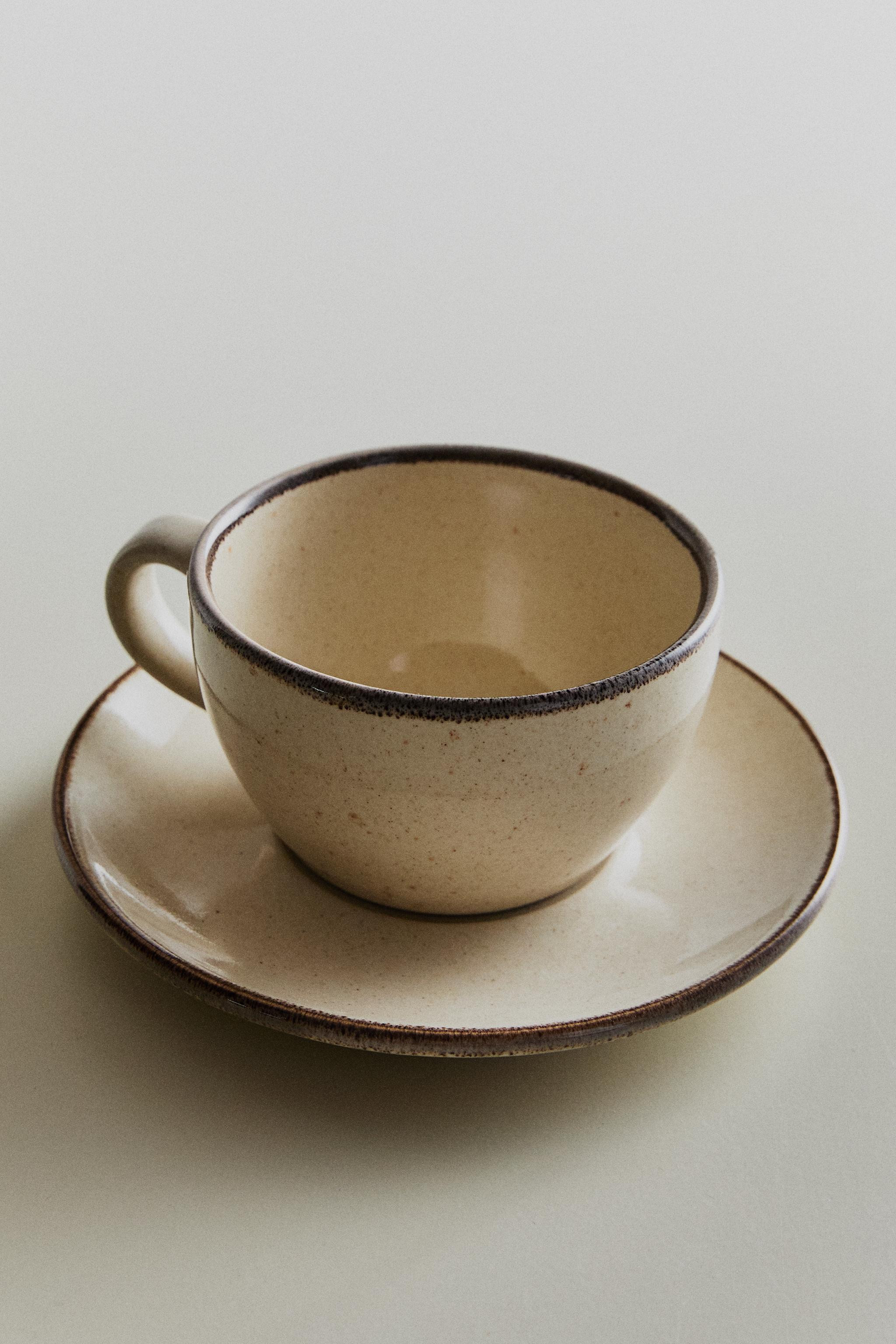 Stoneware teacup and dessert plate in an antique finish and a darker shade on the rim. | Zara UK