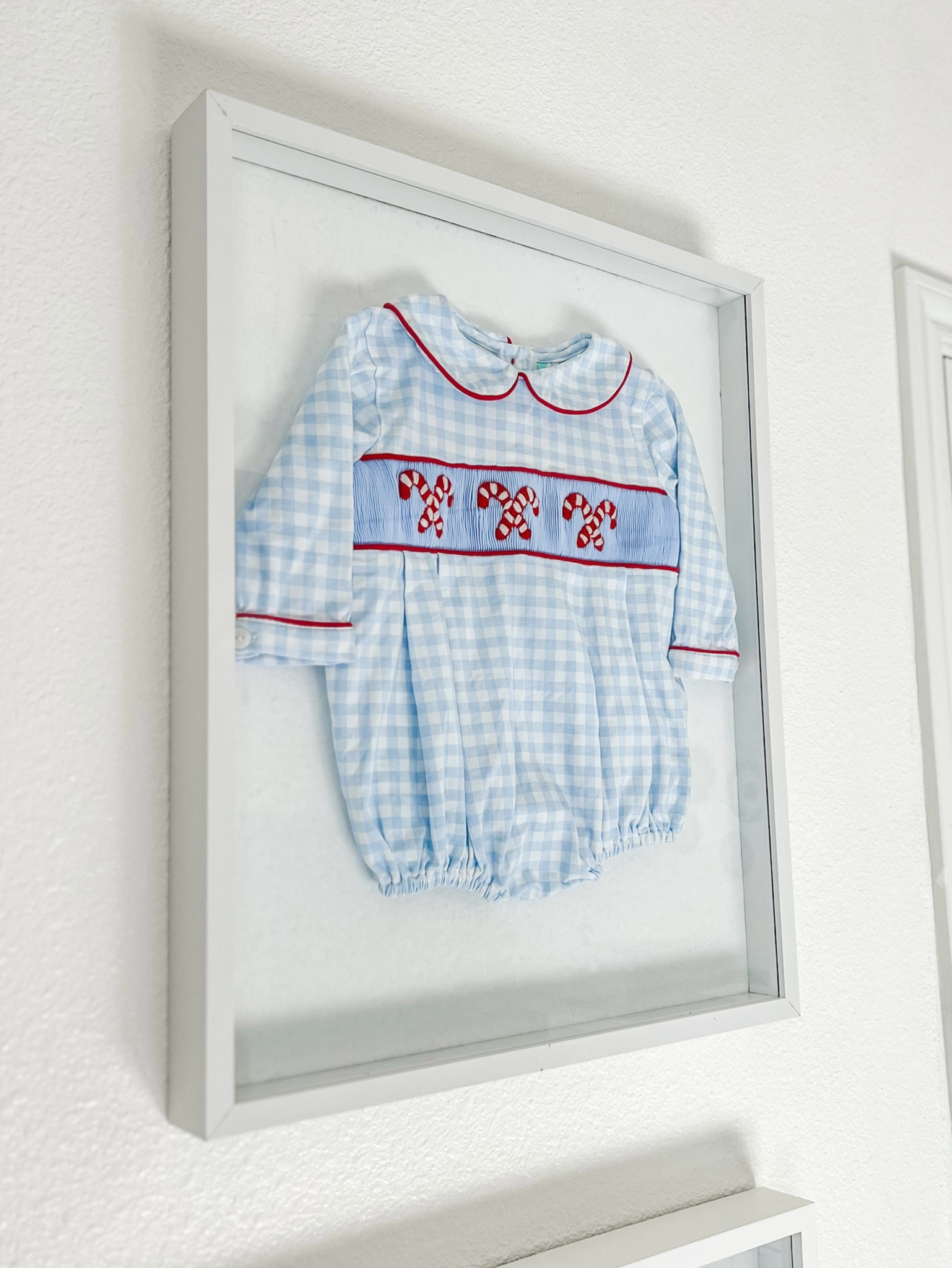 Shadow box with last year’s Christmas outfit ❤️❤️❤️ One of my favorite features in B’s nursery. 

Blue gingham smocked candy cane bubble / Little boy classic Christmas outfits / 

#LTKHome #LTKKids #LTKHoliday