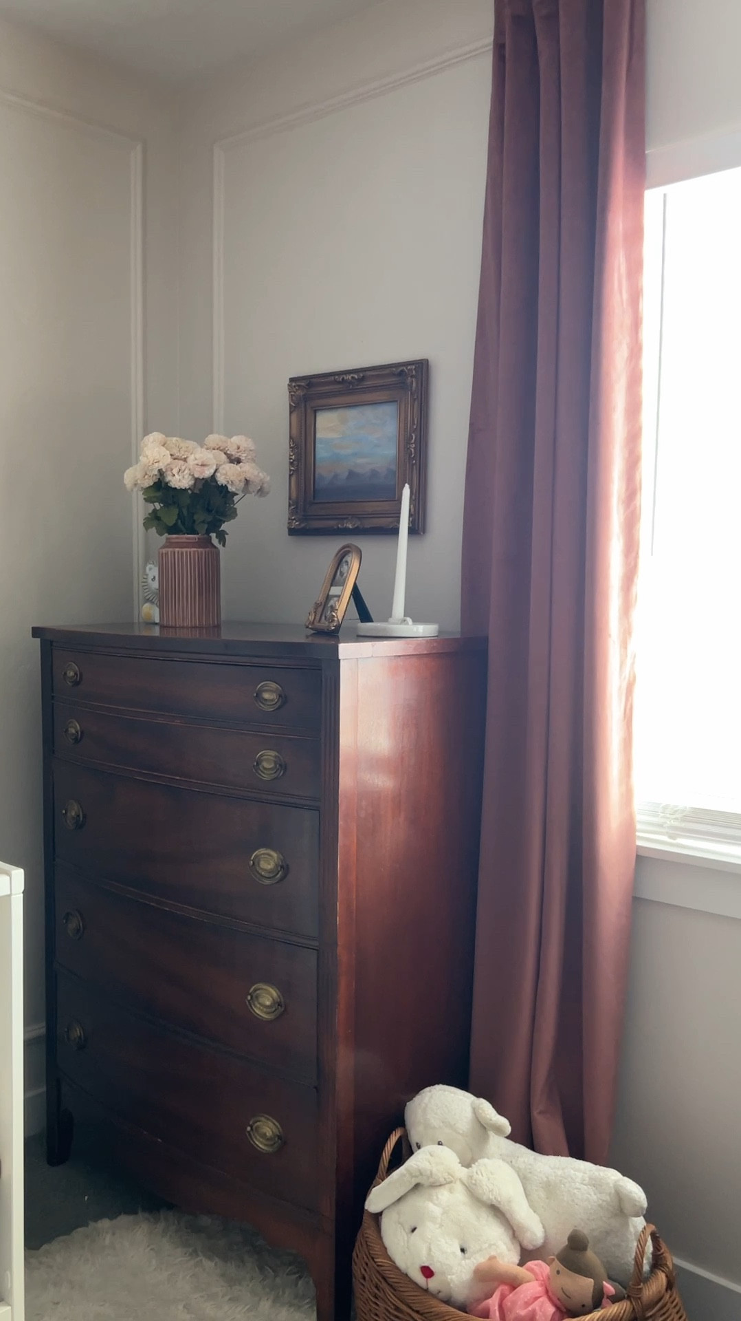 This dresser finally completed our baby girl nursery and I am loving it both for the aesthetic and the function. Finally no more piles of clothes sitting around. And it’s fun to have another surface to style in here too. 
These mums look like they could also be dahlias they are such a good faux flower. They add the perfect touch to this corner and are great for fall decor too. 

Nordic ceramic taper candle holder with handle and tray
Arched gold frame
Brown ribbed ceramic vase
Vintage gold frame
Vintage tallboy dresser
Velvet curtains 
Raspberry curtains 
Soft rug
Sheepskin rug 
Sophisticated classy nursery decor



#LTKHome #LTKSeasonal #LTKFindsUnder50