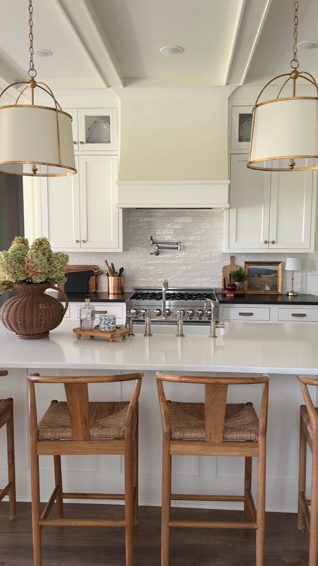 Classic white kitchens never go out of style 🤍 We wanted ours to feel warm + timeless, so we layered in wood barstools, engineered wood floors, wicker accents, warm metals (brass cup pulls + copper decor), and contrasted it all with black quartz countertops around the perimeter and a marble look quartz for the island. 

For finishes, we chose satin-glazed subway tile for the backsplash and polished nickel for the plumbing fixtures — including the bridge faucet + pot filler ✨ Our inset cabinets are color-matched to Benjamin Moore White Dove, which is also our wall color, for a seamless look.

I was not able to link our rug runner but it is Joon Loloi’s Morey washable rug. 

#KitchenDesign #ModernTraditional #WhiteKitchen #HomeStyling 

#LTKHome #LTKHome