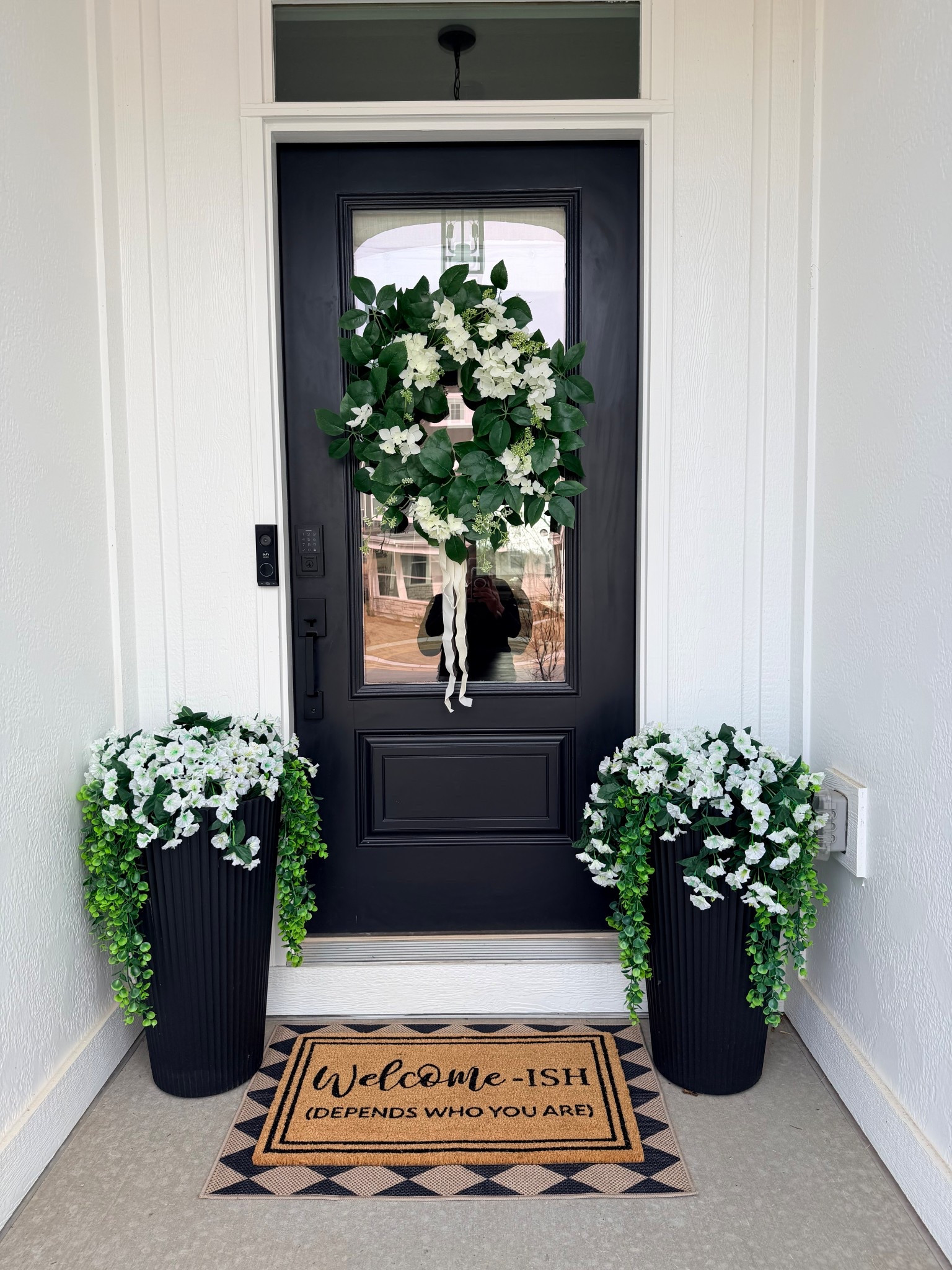 Little entry moment that makes me smile every time I come home. 🤍

A classic black door, oversized planters, fresh greenery, and a simple wreath instantly elevate a front porch. I love keeping the palette neutral and timeless, then adding a little personality with the doormat.

#LTKOver40 #LTKSeasonal #LTKHome