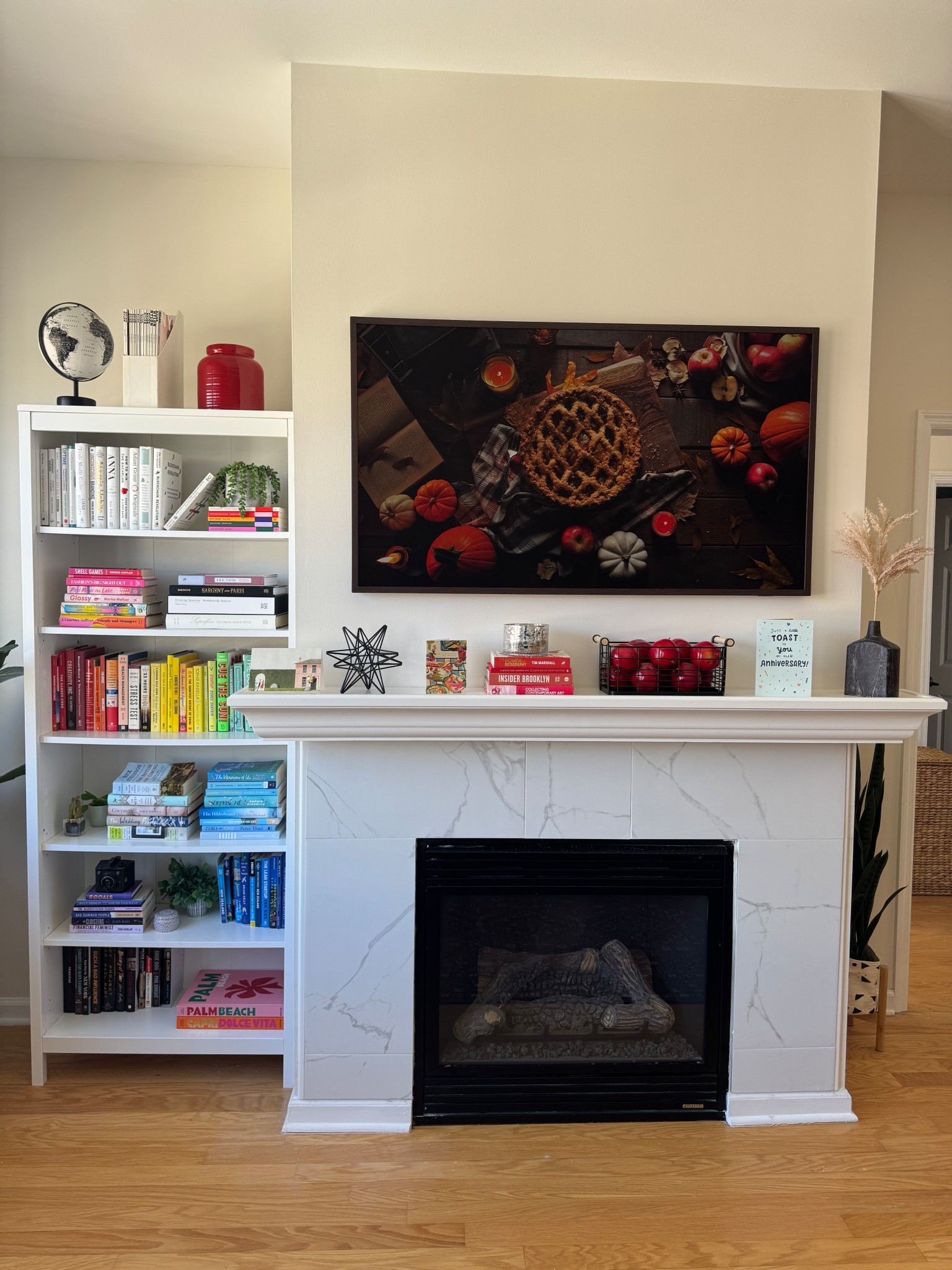 The results of our fireplace makeover! We added this marble-look porcelain tile to the fireplace to create a facing for it and added a white trim and I found this 6 ft mantel shelf on Wayfair that fit perfectly. We mounted the Samsung Frame TV over the fireplace and added the modern brown frame to it, I love how much it looks like art and how it blends in. We also have the bookcase right next to it, I love how they look next to each other.

#LTKFindsUnder100 #LTKHome