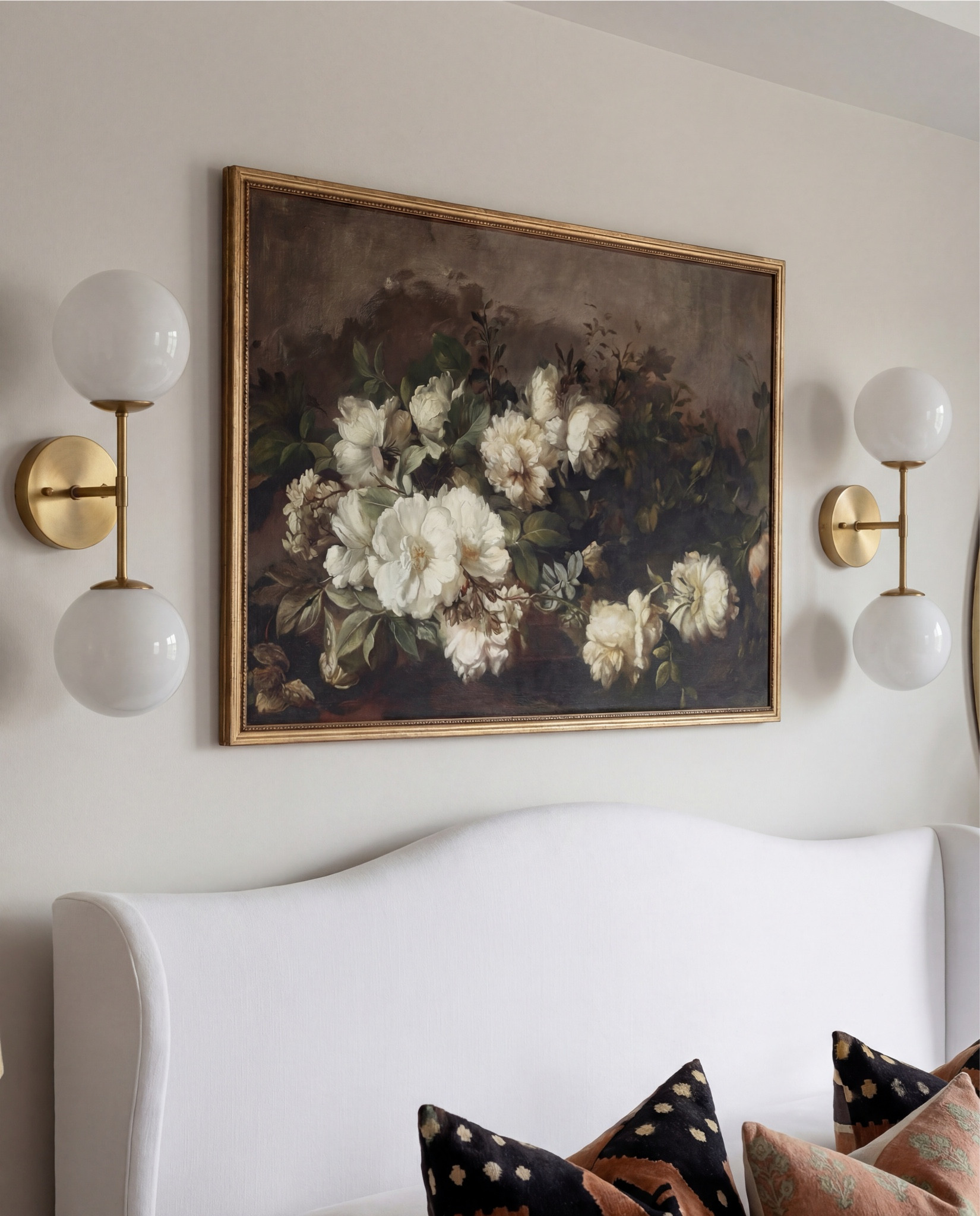 Shop the Look:
• White upholstered wingback bed frame
• White cotton duvet cover + pillow shams
• Textured throw pillows (rust + black patterned)
• Chunky knit throw blanket (warm brown)
• Vintage-style brown area rug
• Dark wood nightstands with brass knobs
• Ceramic table lamp (neutral glaze)
• Brass globe wall sconces
• Framed floral artwork (muted tones)
• Arched brass wall mirrors
• Upholstered bench at foot of bed (camel brown)
• Cream accent chair with wood arms
• Black fluted dresser with brass pulls
• Round black fluted end table 
•Fecor books 
• Large ceramic floor vase (earthy clay tone)
• Decorative wood bead garland
• Sheer white curtain panels
•Round decor bowl tray 
•Wood jewellery box 
•Terracotta bowl 

#LTKHome #LTKSaleAlert