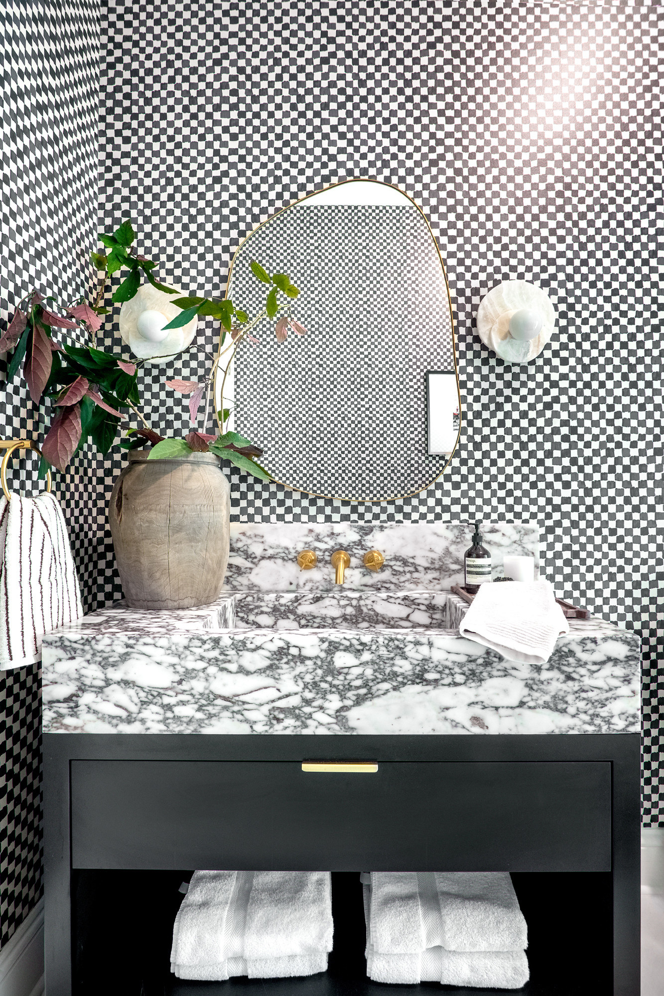 Bold, timeless, and just a little unexpected. This black-and-white powder bath proves that pattern play and natural texture can live in harmony. We paired a checkerboard wallcovering with a statement marble vanity, matte-black base, and brass fixtures for a look that feels both modern and classic. Add a sculptural mirror, organic vessel, and plush white towels to soften the contrast. Shop the look below and recreate this boutique-hotel vibe at home. 

 #LTKHome