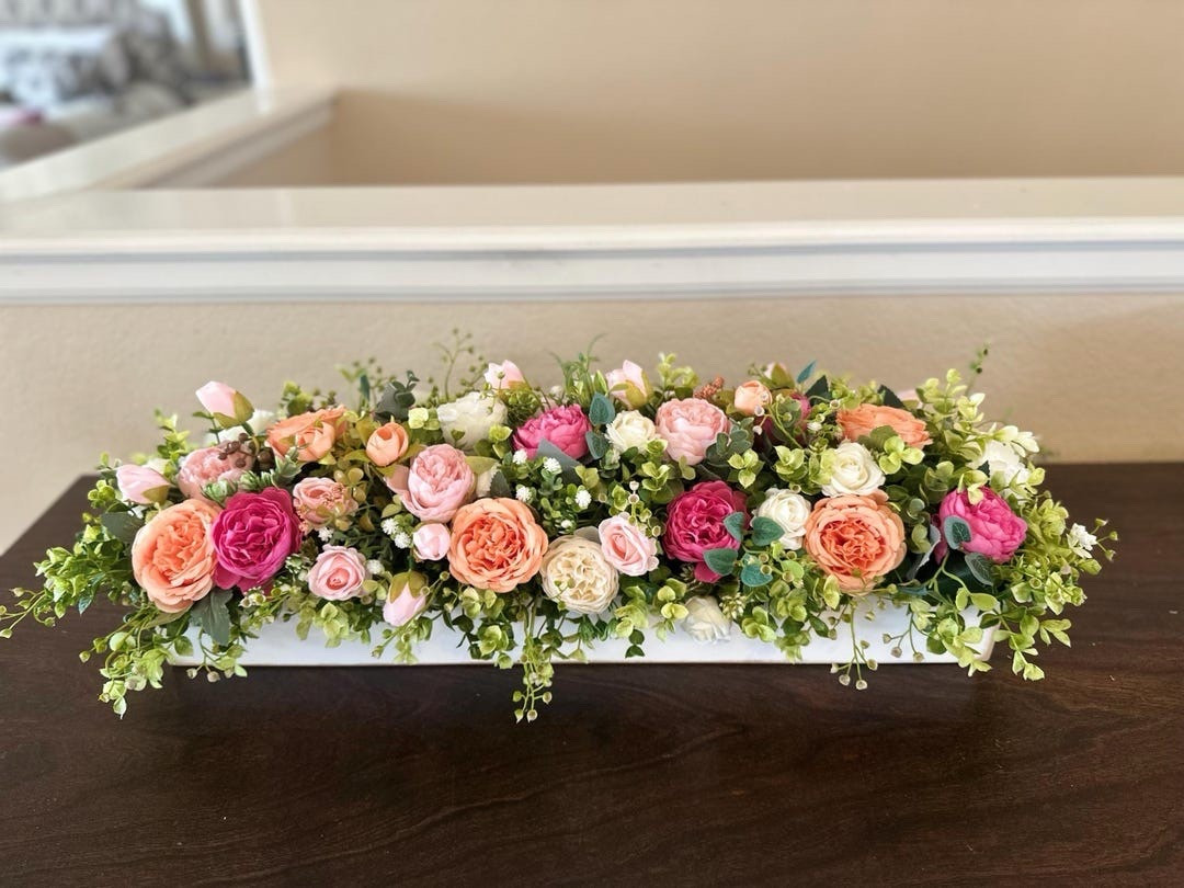 Soft, romantic, and beautifully customizable—this farmhouse centerpiece is designed to bring warmth and charm to your table. Featuring delicate mini roses and peonies nestled in lush greenery, each arrangement is set in a handcrafted pine wood box finished to match your style. With multiple size and finish options, it’s the perfect piece to elevate everyday dining or create a stunning focal point for gatherings. #LTKhome #farmhousedecor #tabledecor #floralcenterpiece #homestyling #cozyhome #springdecor #decorinspo

#LTKSeasonal #LTKWedding #LTKHome