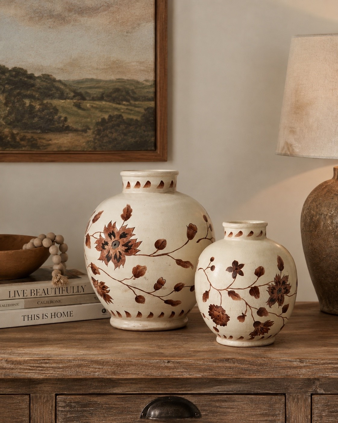 A cozy neutral console table moment with vintage-inspired floral ceramic vases, warm wood tones, stacked coffee table books, a landscape print, and soft ambient lighting. Such a pretty styling idea for an entryway, living room, or hallway console if you love organic modern, collected, and timeless home decor. Save this for warm neutral decorating inspiration 🤎

#LTKHome