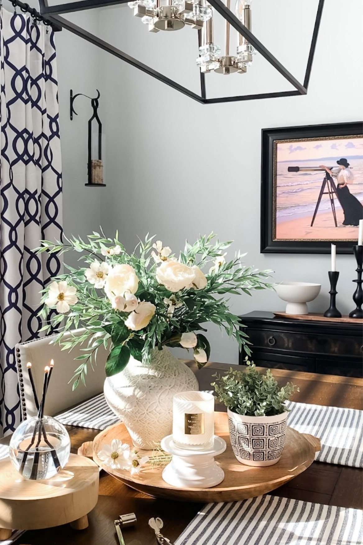 Spring styling with elegant black chandelier, beautiful white roses, Blue and white curtain panels, black cabinet on sale, Cosmo florals with greenery, favorite textured vase, beach print, black candleholders, candle accessories, wood tray, pedestal bowl, wood riser. Home decor accessories, interior styling. 

#LTKhome #LTKunder50 #LTKsalealert