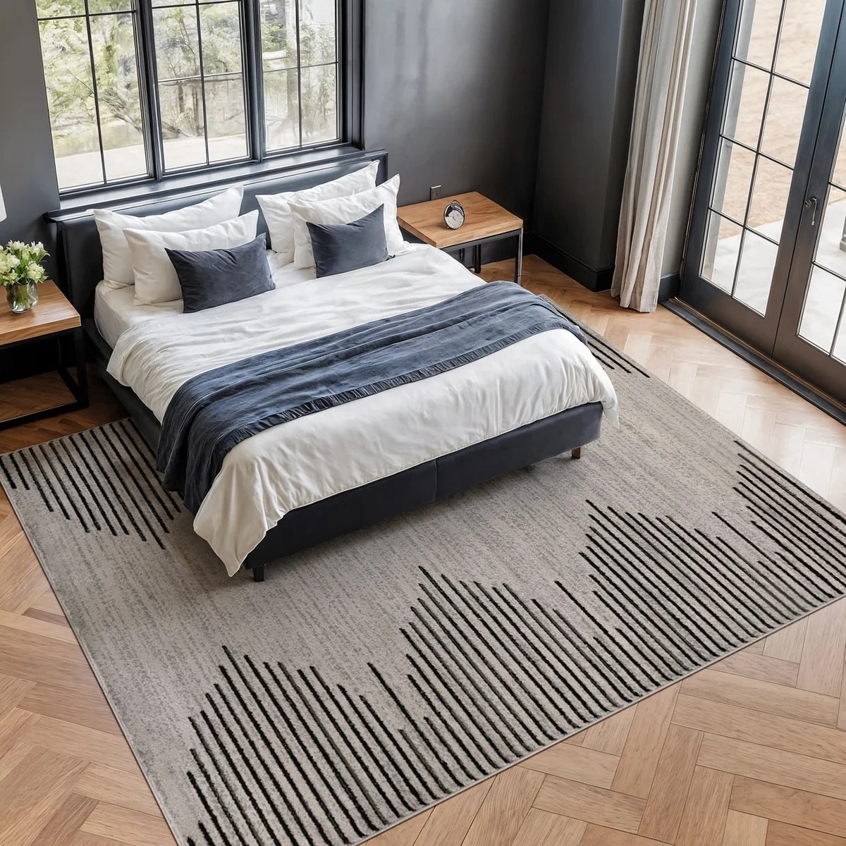 Create a bold, modern bedroom with this geometric area rug from Wayfair paired with a sleek upholstered platform bed. The cream, black, and gray rug features a striking linear geometric pattern that adds contrast and texture, while the black upholstered bed frame creates a clean, sophisticated focal point. Styled with crisp white bedding, layered accent pillows, and warm wood nightstands, this combination is perfect for modern, contemporary, and minimalist bedrooms.