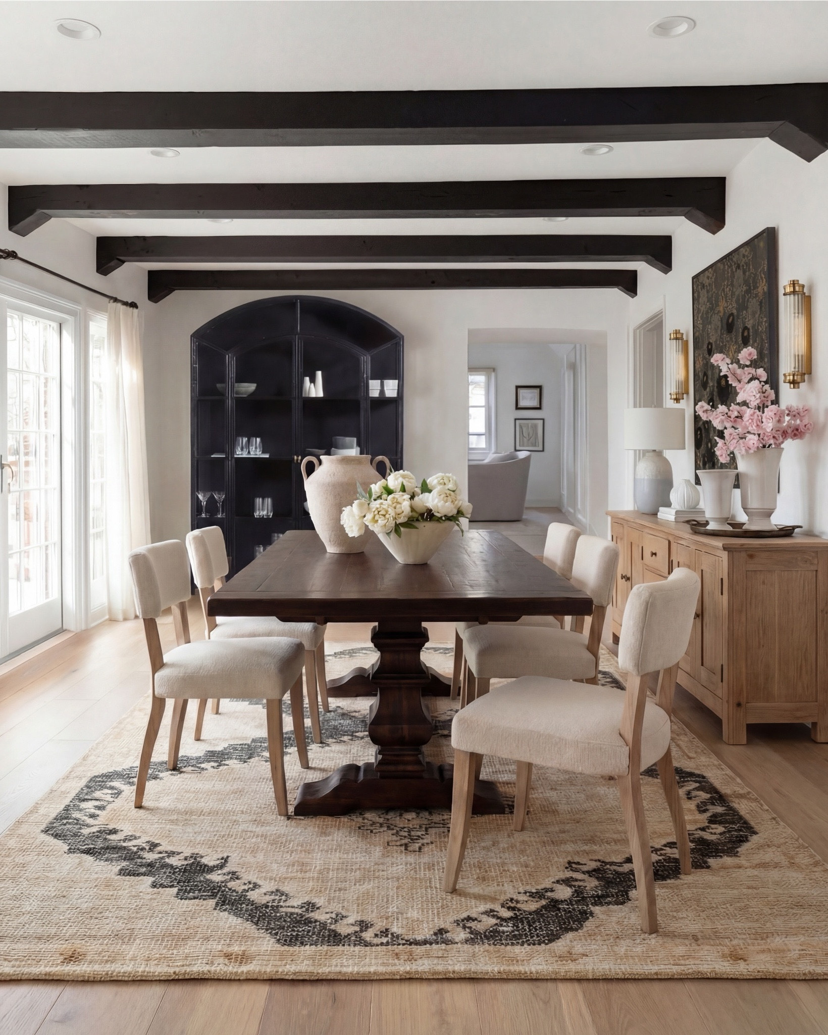 Shop the Look:
• Dark wood pedestal dining table
• Cream upholstered dining chairs with light wood legs
• Large neutral area rug with charcoal medallion pattern
• Black arched display cabinet / hutch
• Light wood sideboard / buffet cabinet
• Large ceramic floor vase (neutral tone)
• White ceramic bowl with white florals (peonies or roses)
• Pink faux cherry blossom stems in white vase
• Neutral ceramic table lamp with white shade
• Tall brass wall sconces with glass detailing
• Framed botanical artwork (set of four)
• Dark abstract wall art (large statement piece)
• White decorative vases (assorted sizes)
• Light linen curtains

#LTKSaleAlert

#LTKsale #LTKhome