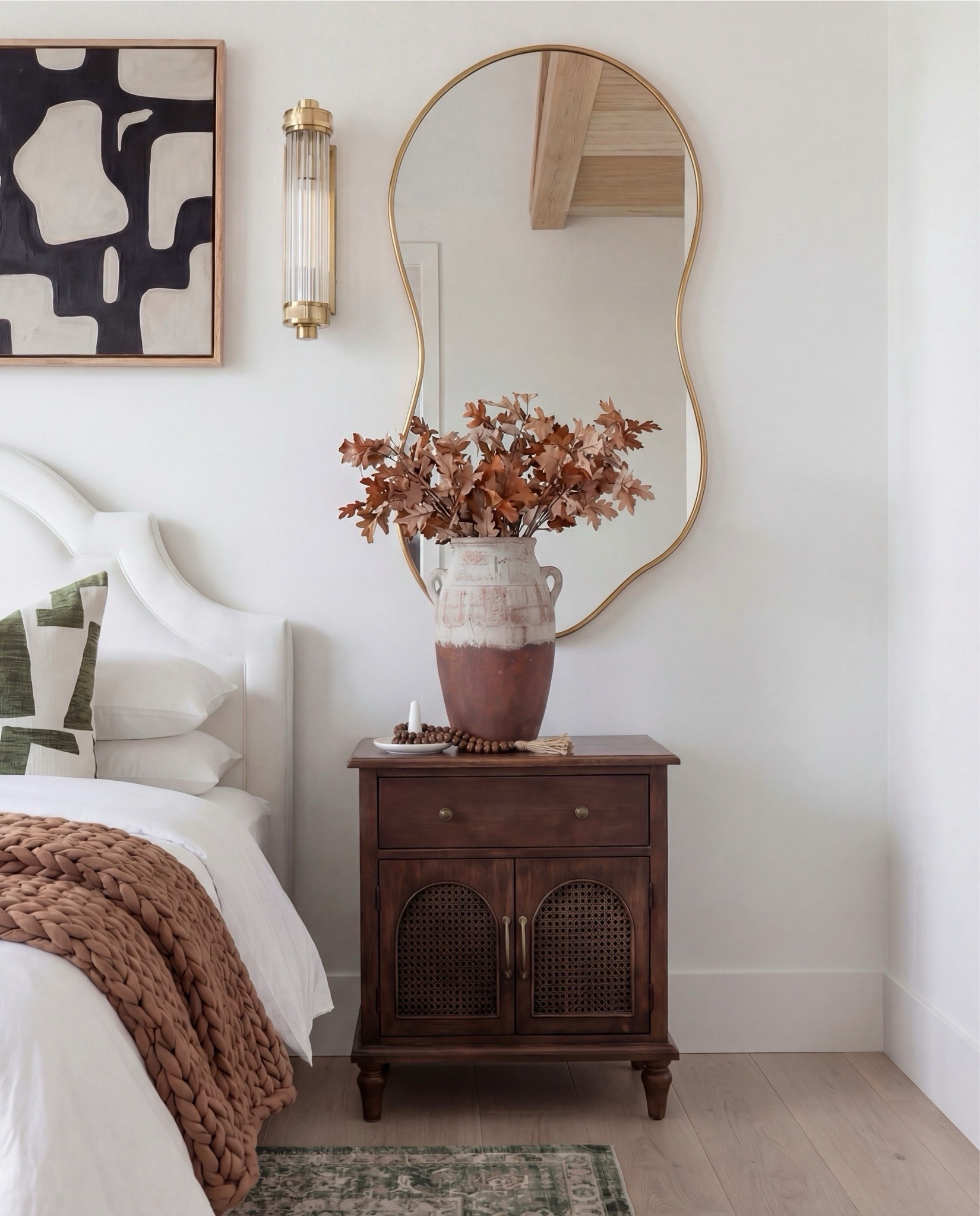 Shop the Look:
• White upholstered arched headboard bed
• White cotton duvet cover + pillow shams
• Green vintage-style area rug (distressed pattern)
• Brown chunky knit throw blanket
• Dark wood nightstands with cane doors
• White ceramic table lamp (round base)
• Brass wall sconces with glass shades
• Organic shape gold wall mirrors
• Black and beige abstract framed wall art
• Green geometric throw pillows
• Upholstered brown bench (channel tufted)
• Dark wood dresser with brass pulls
• Round ivory accent chair
• Cream throw blanket (soft knit texture)
• Tall brass floor lamp with white shade
• Decorative book stack (neutral tones)
• Small wood decorative box
• Brass round tray
• White pedestal decorative bowl
• Marble candle holders with brass rings
• Taper candles (ivory)
• Large ceramic vase with dried stems

#LTKHome #LTKSaleAlert