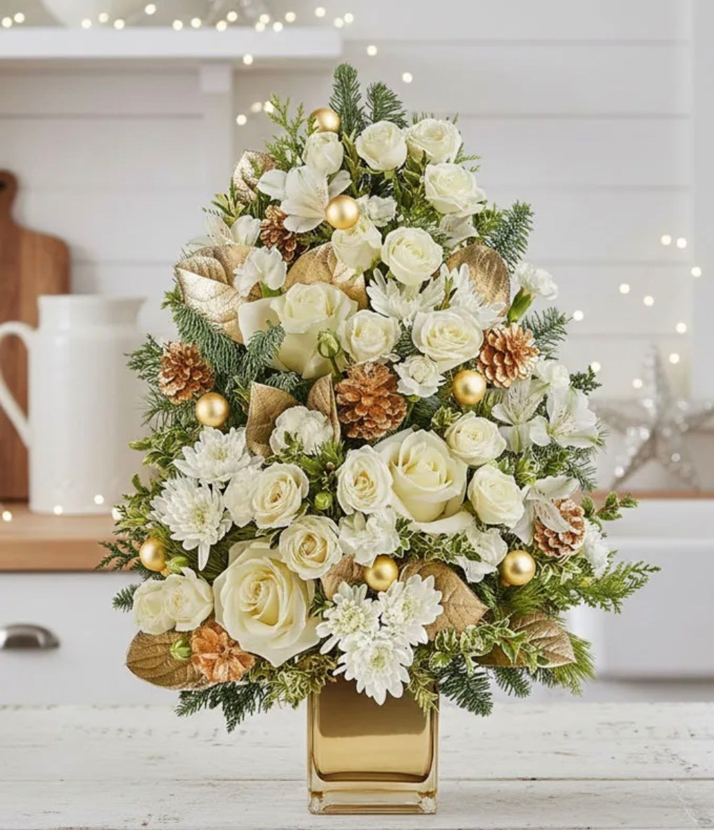 ✨ Note that these are fresh flowers ✨ Delight someone special with this elegant Holiday tree-shaped floral arrangement. Featuring beautiful white roses, carnations, and chrysanthemums accented with gold pinecones, ornaments, and lush evergreens, it creates a stunning holiday centerpiece. Presented in a stylish gold vase, it's a perfect gift to bring festive cheer and brighten any space this season. This DELUXE floral arrangement is ON SALE and is under $60.

Includes:
• White Roses
• White Spray Roses (Deluxe & Premium Sizes)
• White Alstroemeria
• White Miniature Carnations
• White Cushion Spray Chrysanthemums
• Noble Fir
• White Pine
• Festive Seasonal Greenery
• Gold Accents
• Gold Mirrored Cube Container
• Complimentary Card Message

Keywords: Hostess gift, holiday flowers, holiday gift, floral arrangement, holiday tree, gifts for her, gifts for them

#LTKHoliday #LTKSaleAlert #LTKSeasonal