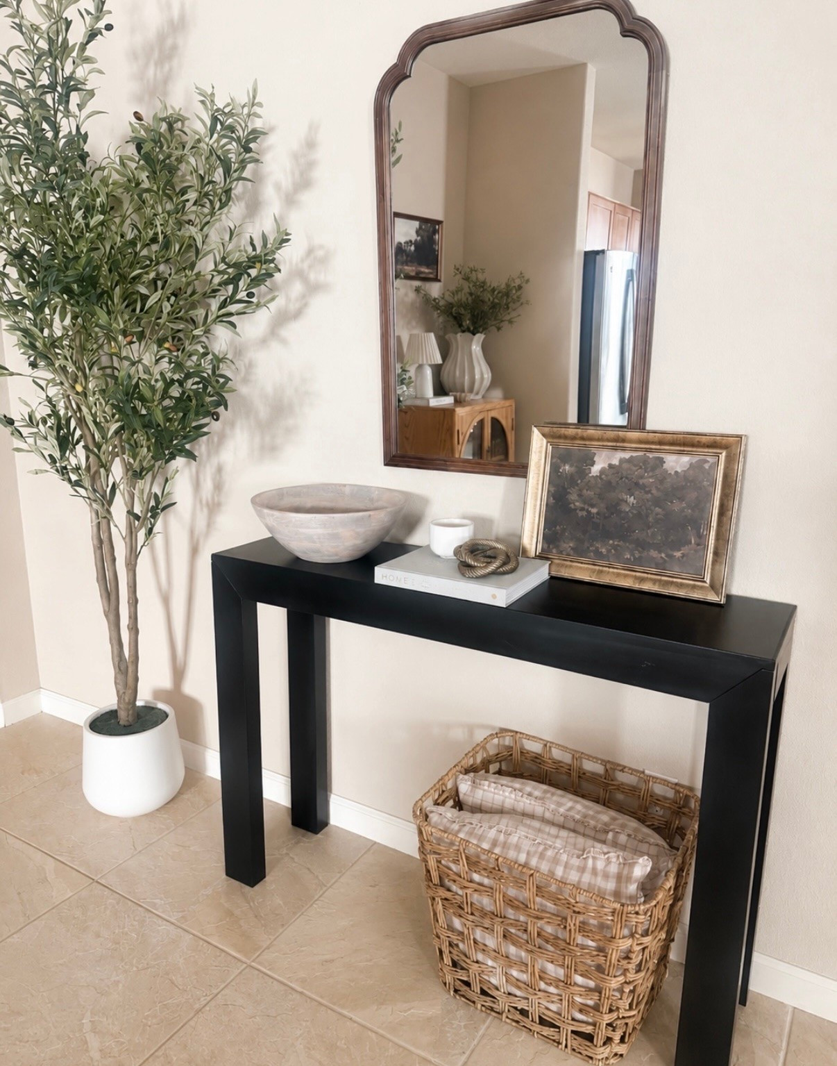 ✨ one of my favorite little entryway corners lately 🤍

I love mixing warm wood tones, black accents, woven textures, and greenery because it makes a space feel layered without needing a ton of decor

styled this area with:
✔ oversized olive tree
✔ arched mirror
✔ simple black console
✔ woven basket storage
✔ neutral layered decor pieces

such an easy way to make an entry feel more cozy, elevated, and pulled together ✨