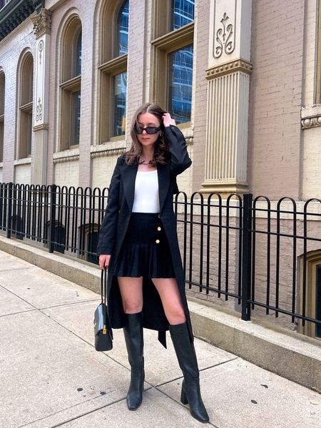 Black trench coat, pleated skirt, knee high boots 