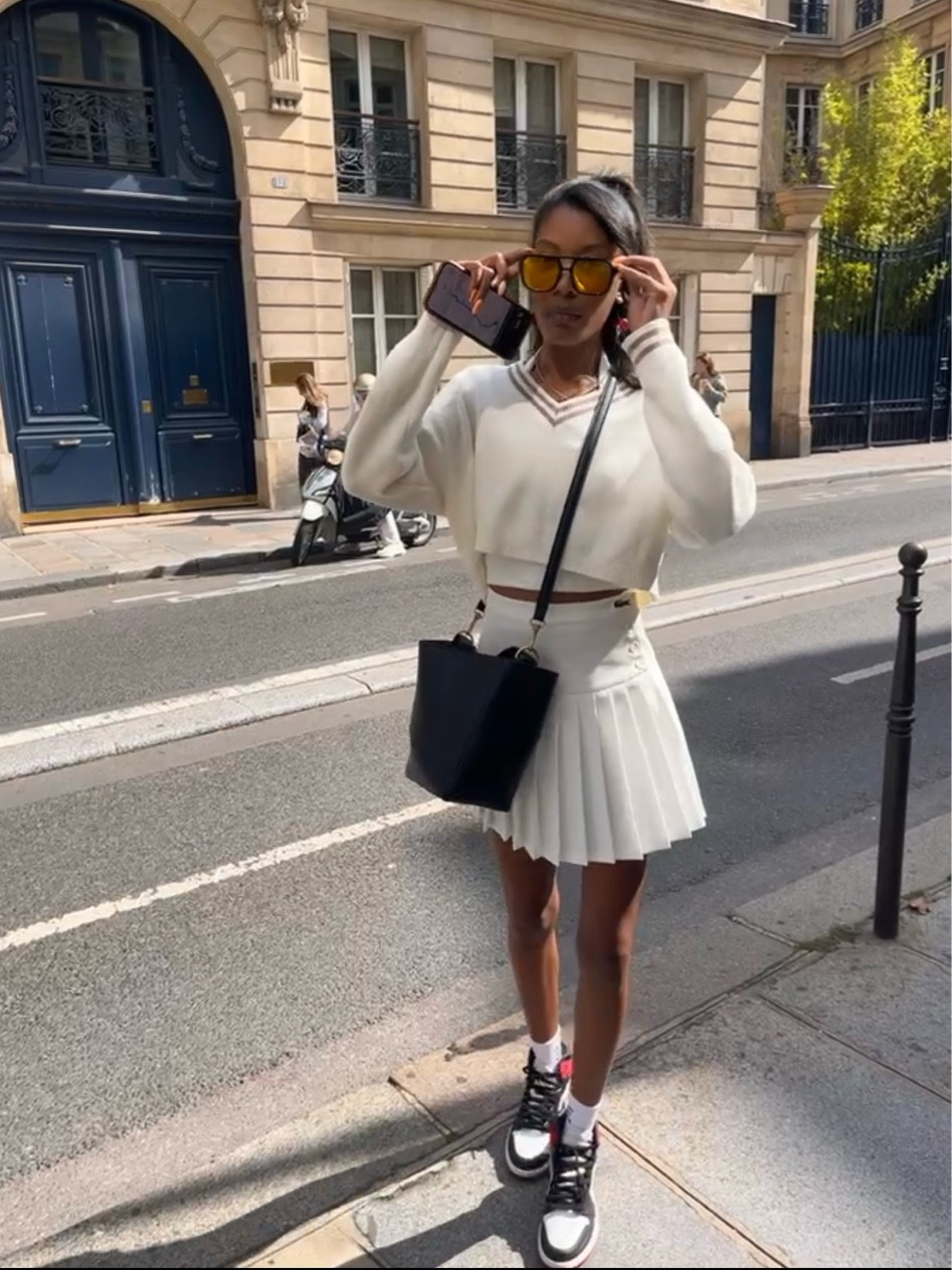 Paris Summer Olympics OOTD! Wearing small in the sweater & size 2 in the skirt. 

✨Top - Forever 21 white halter 
✨Sweater - Alo Tennis Club Sweater Knit V-Neck Pullover 
✨Shoes - Nike Wmns Air Jordan 1 Retro High 'Satin Black Toe’
✨IDGAF socks
✨Cherry earrings & retro aviators from temu

#LTKSaleAlert #LTKStyleTip #LTKTravel