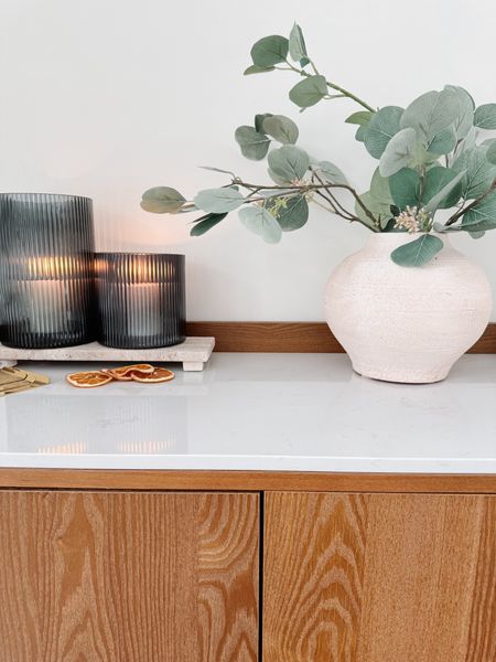 Bar cabinet styling. ✨

White vase, eucalyptus stems, smoke glass candle holders, travertine 

#LTKhome
