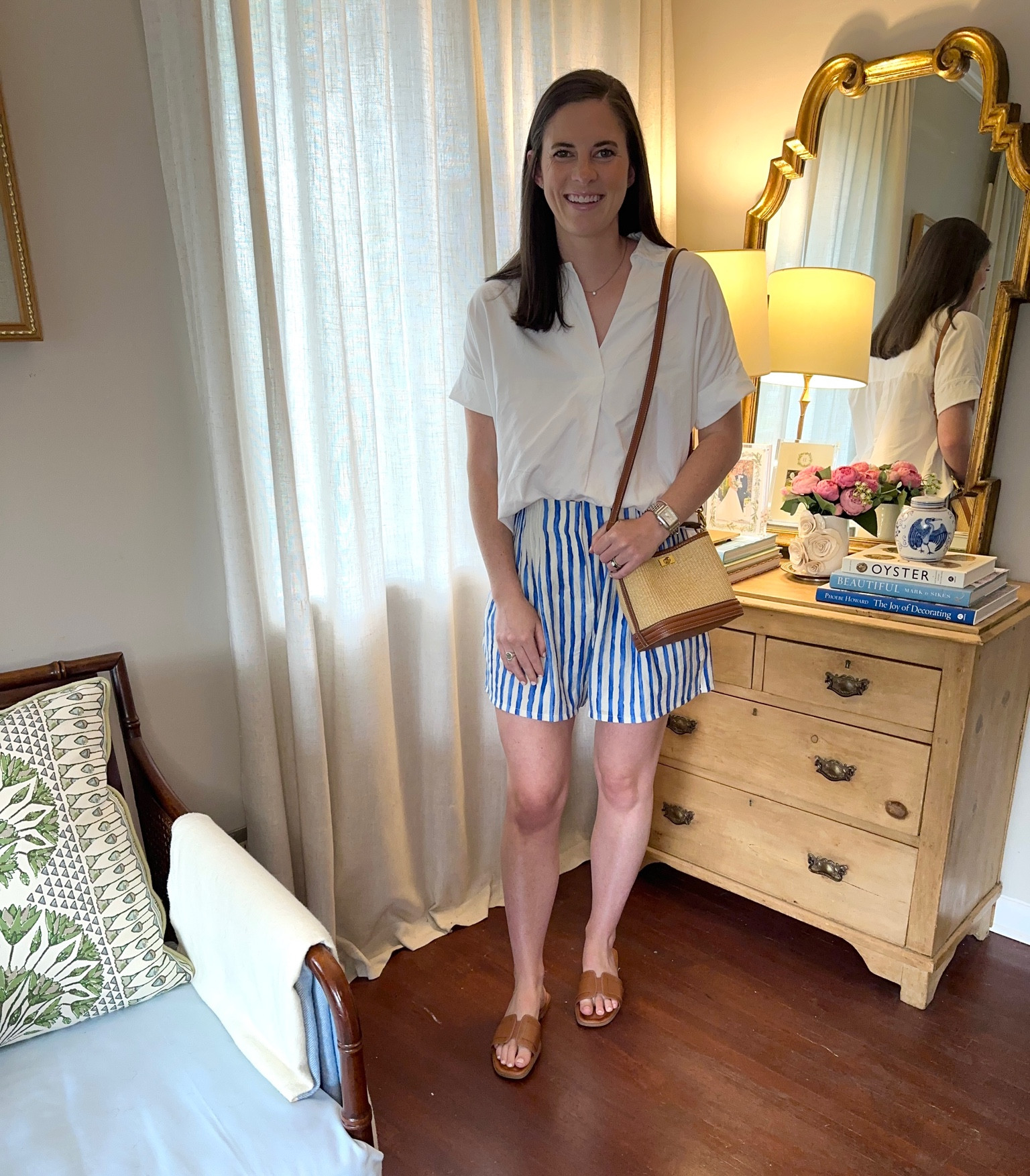 Fourth of July outfit inspiration. Casual blue and white striped shorts, white collared shirt, tan sandals, and mango raffia natural crossbody bag