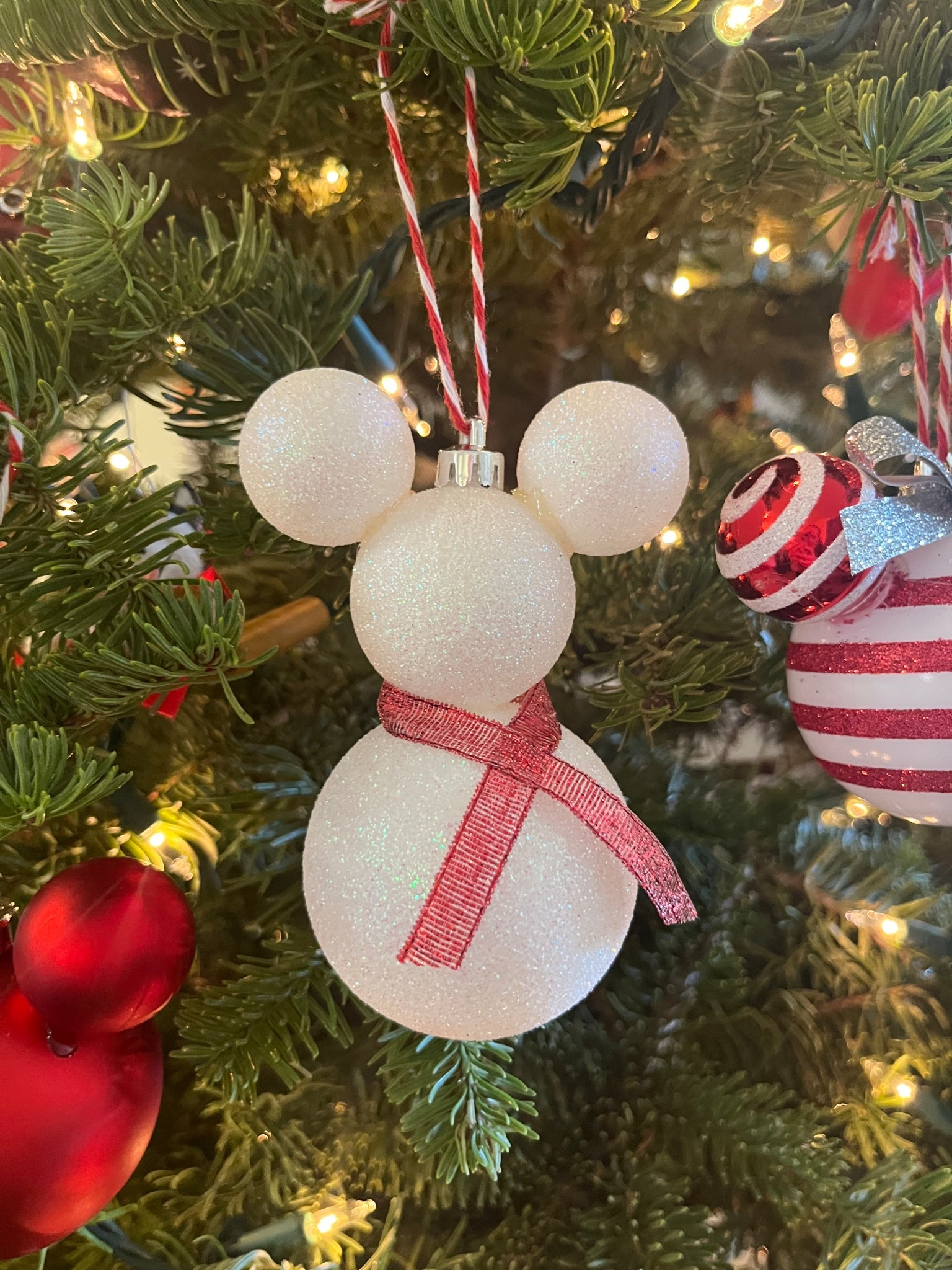 DIY Mickey snowman ornaments using white sparkly shatterproof ornaments, a high temp mini glue gun, red sparkly ribbon, and red twine. These are a fun and easy Disney Christmas craft  

#LTKKids #LTKHoliday #LTKSeasonal