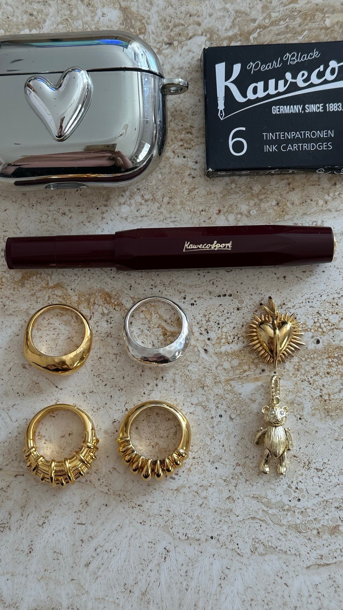 Flatlay Friday, but make it romantic. A burgundy Kaweco pen and a silver heart AirPods case scattered with dome rings, a raffia twist and charms - the kind you keep close, even when no one else sees them, because they feel like little secrets. 🐻
.
flatlay jewellery | silver dome ring | gold dome ring | claw ring | raffia ring | bear charm | sacred heart charm | jewellery styling | mixed metals | everyday rings | flatlay friday | elevated jewellery | statement rings