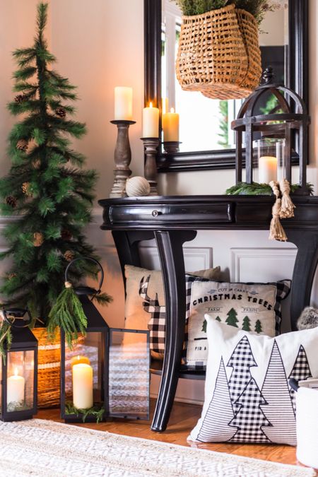 Decorate a beautiful but cozy foyer entryway for the holiday season. Faux pine trees in baskets with candle lanterns. Pillar candles and greenery create a Christmas aesthetic in your home. Cozy pillows add interest in unexpected places. #Christmasdecorating #Christmashomedecor #foyer #entryway

#LTKSeasonal #LTKhome #LTKHoliday