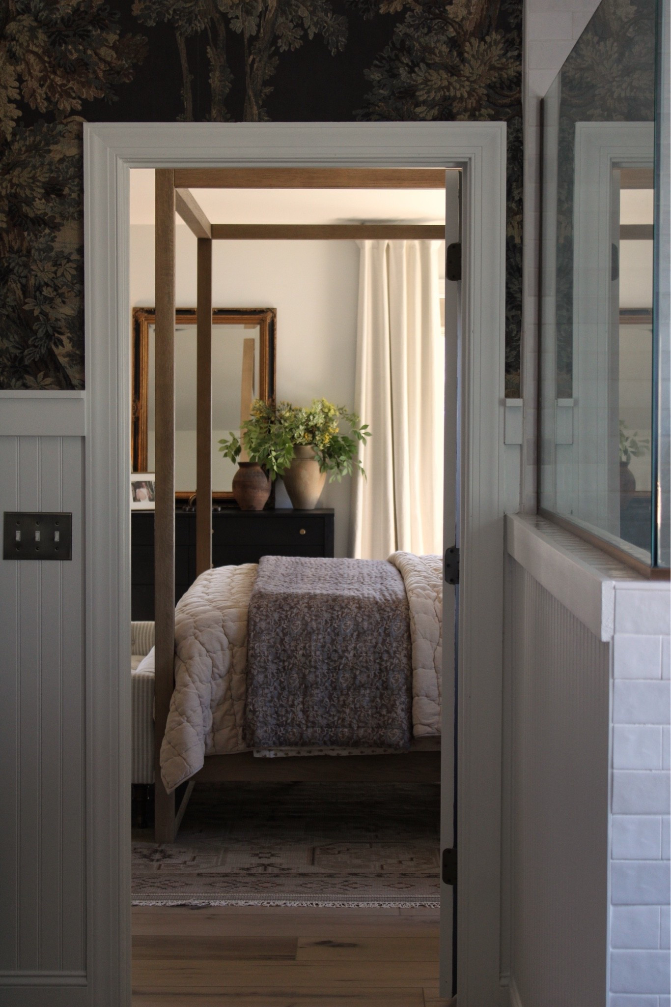Bedroom view from the bathroom. Favorite quilts, ivory curtains, canopy bed, dresser styling