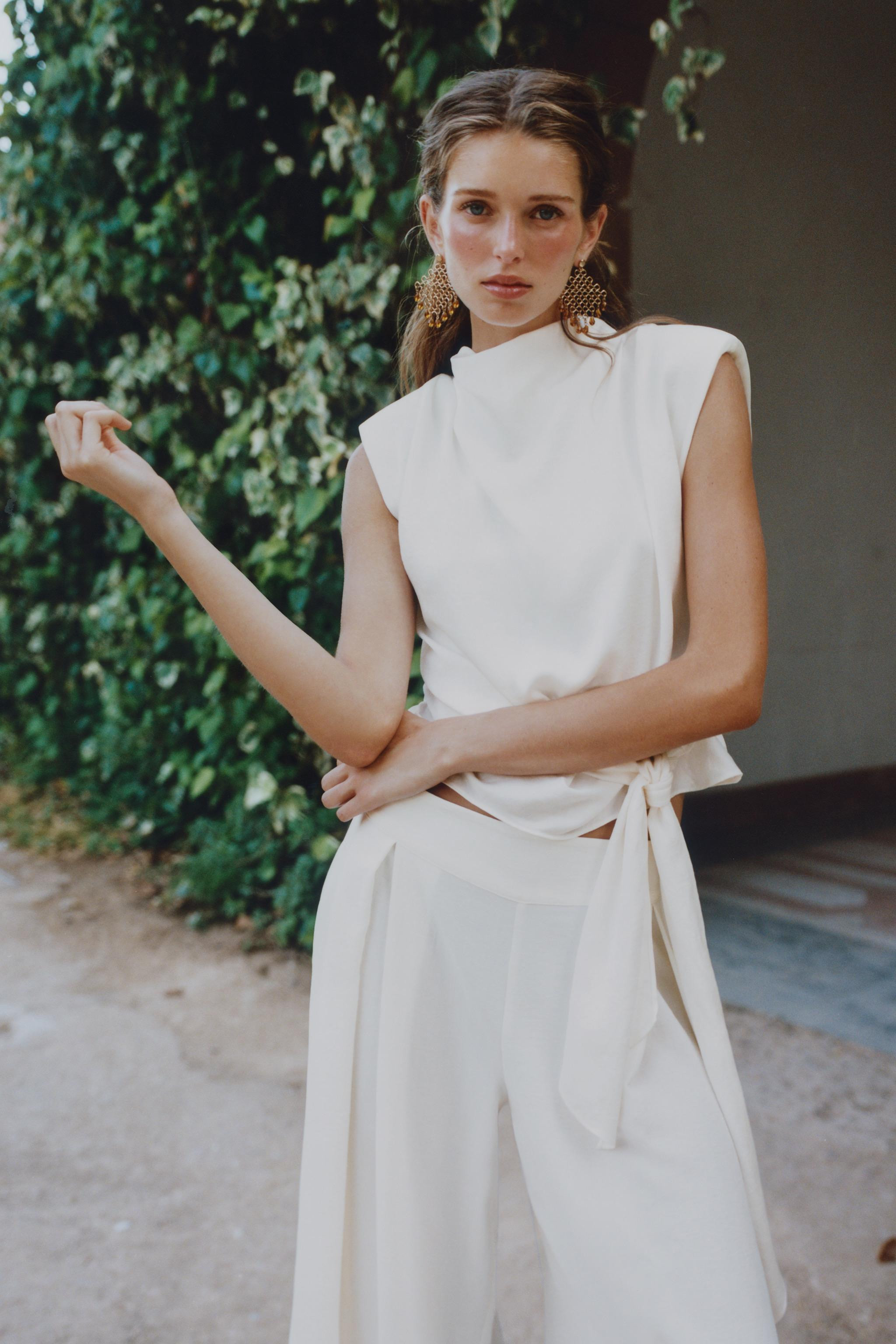 High neck sleeveless top with shoulder pads and pleats. Knot at hem. Back opening with hidden but... | Zara US