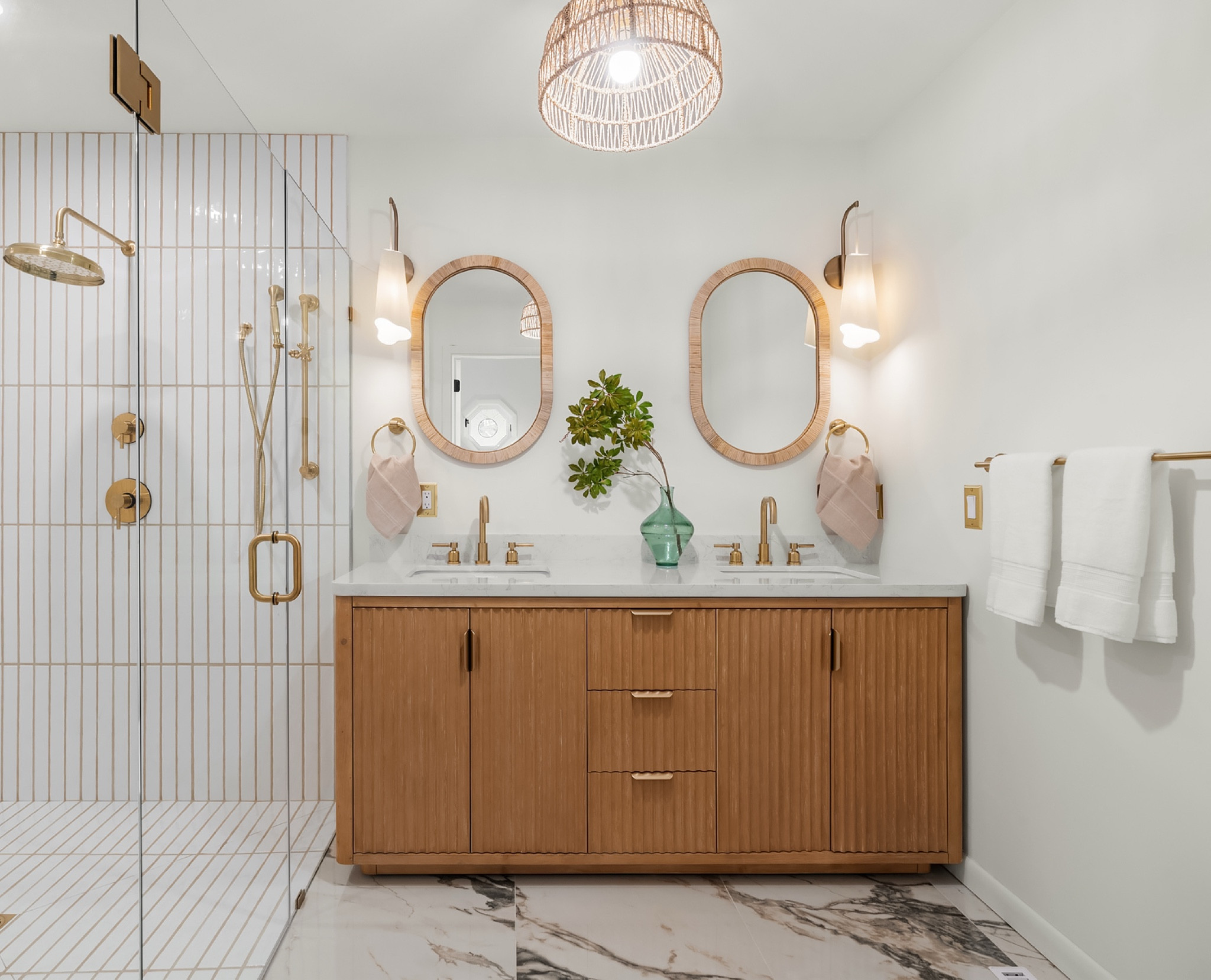 Double vanity with a wood cabinet, brass fixtures, and oval mirrors. Shower with vertical tile and glass enclosure. Linking exact and similar pieces here.

#LTKHome #LTKSaleAlert