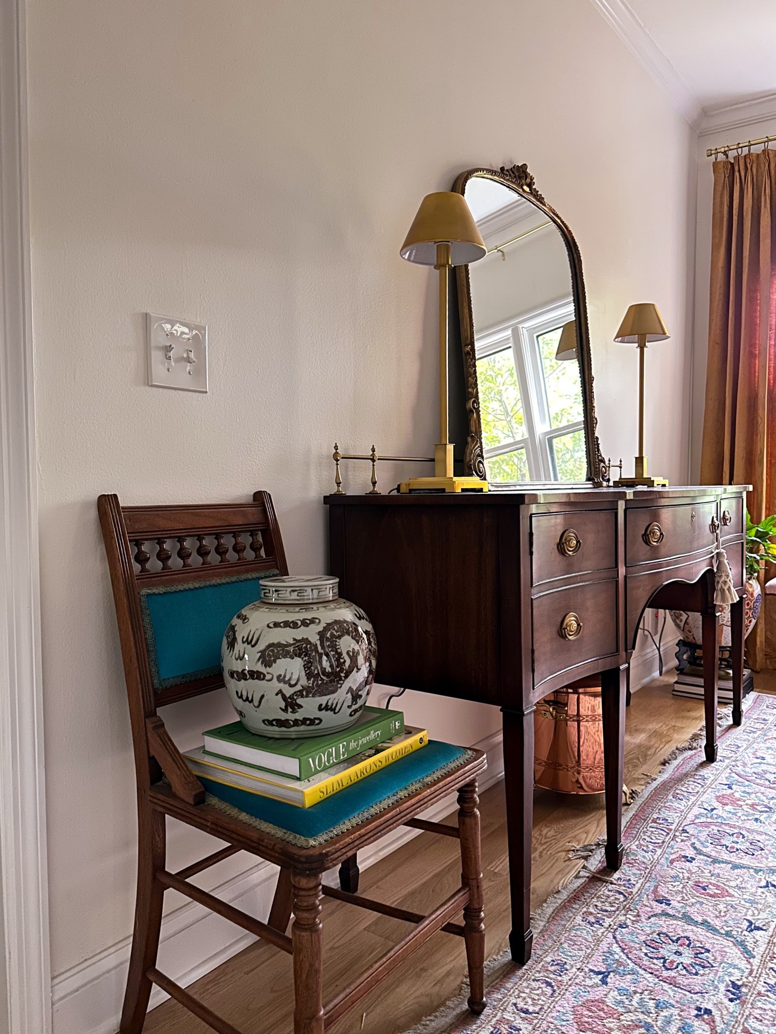 This vignette blends traditional home decor with vintage styling ideas that never go out of fashion. The antique buffet, gilded mirror, and brass lamps create a warm, layered look that feels elevated but approachable. I added a ginger jar and stacked coffee table books for that designer-collected touch. Perfect if you love entryway decor inspiration or classic dining room styling.
