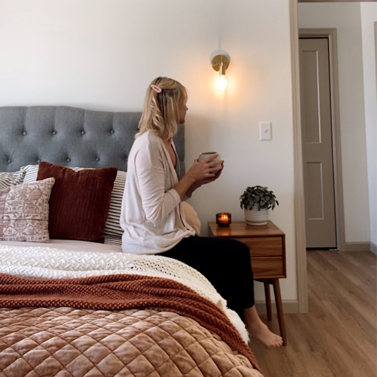 Primary Bedroom featuring peach, rust, and taupe bedding with a mid century modern nightstand  
