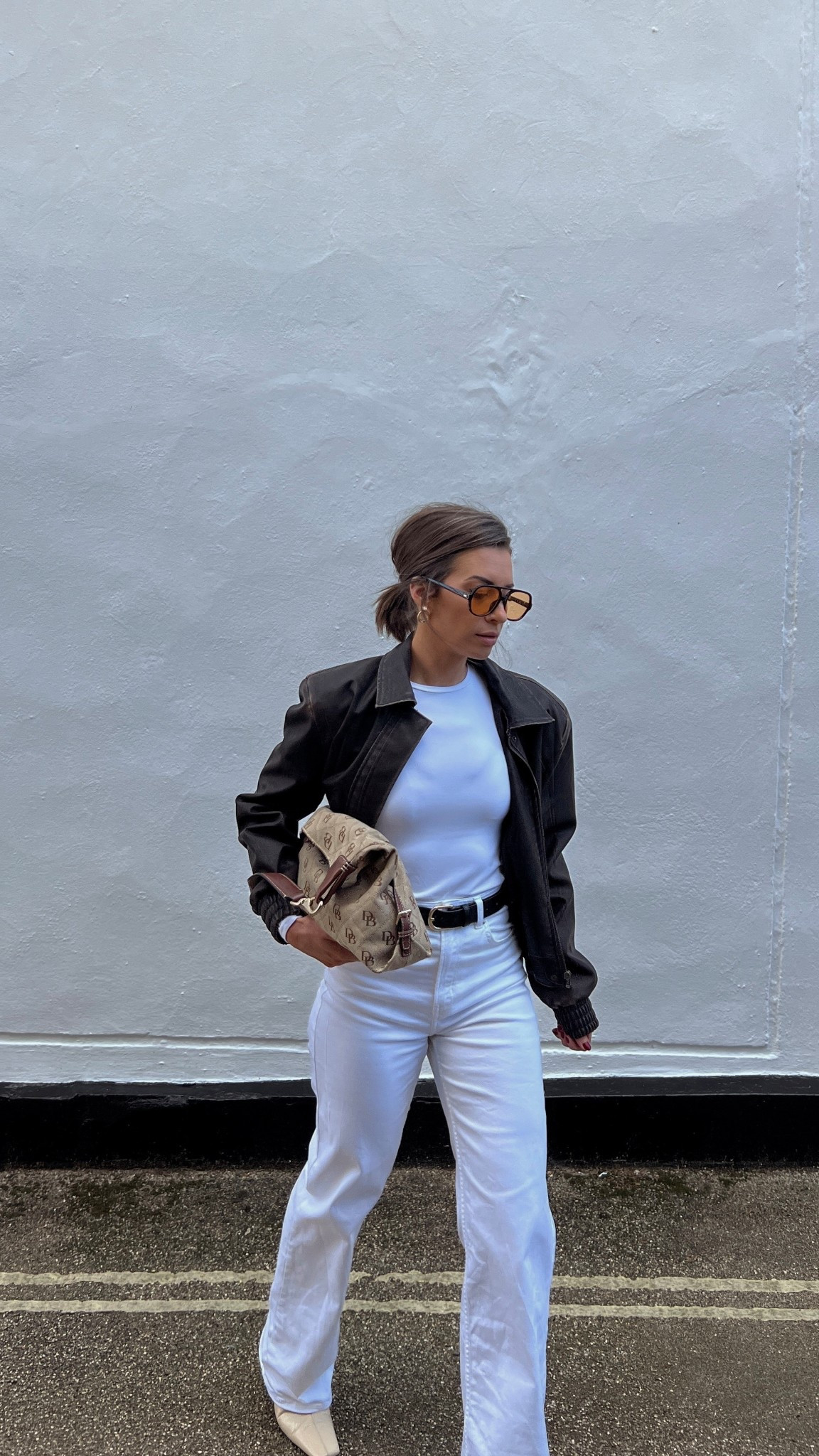 All white outfit. Winter whites. Transitional outfit style inspo. Spring outfit. Brown leather jacket. White denim. Zara boots. Dooney & Burke oversized boho shoulder bag. Yellow lens glasses. Light tinted lens glasses. Lululemon inspired top. 