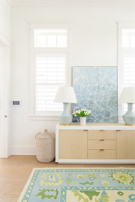 My home office decorated for spring with my linen buffet table, sparkling water art, seafoam lamps, scalloped marble vase with white tulips, woven hamper, and colorful oushak rug! See our full spring home tour here: https://lifeonvirginiastreet.com/2024-spring-home-tour/.
.
#ltkhome #ltksalealert #ltkfindsunder50 #ltkfindsunder100 #ltkseasonal coastal decor, home office decor, storage ideas 

#LTKSeasonal #LTKsalealert #LTKhome