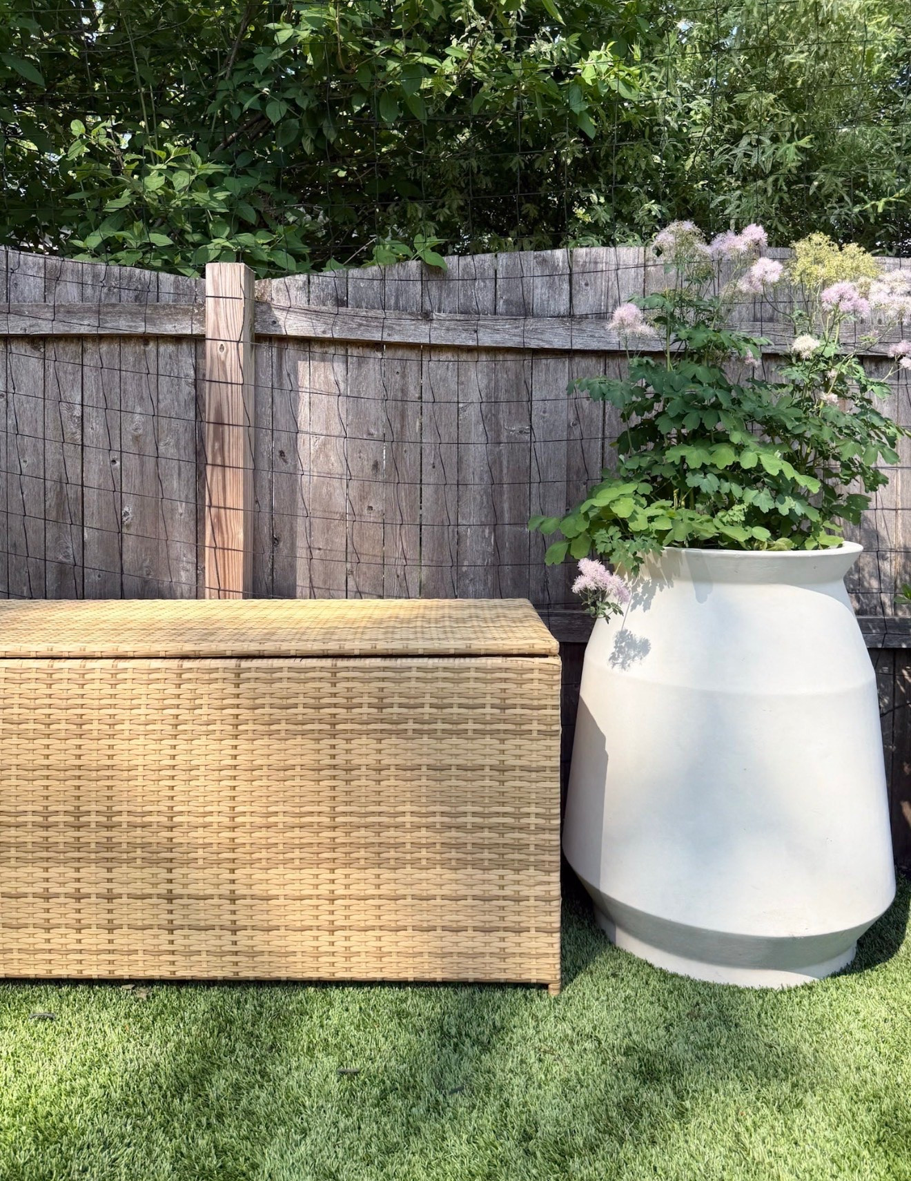 This oversized planter is such a statement piece for an outdoor space. I love the mix of the soft neutral planter, natural woven storage bench, and airy greenery because it gives the backyard that relaxed coastal garden feel while still looking elevated and timeless. Outdoor planter ideas, Neutral outdoor decor, Backyard styling inspiration, Coastal patio decor, Garden styling, Outdoor storage bench, Patio decorating ideas, Large outdoor planters, Backyard oasis inspiration, Outdoor living space, Summer patio decor, Girl on the Hudson