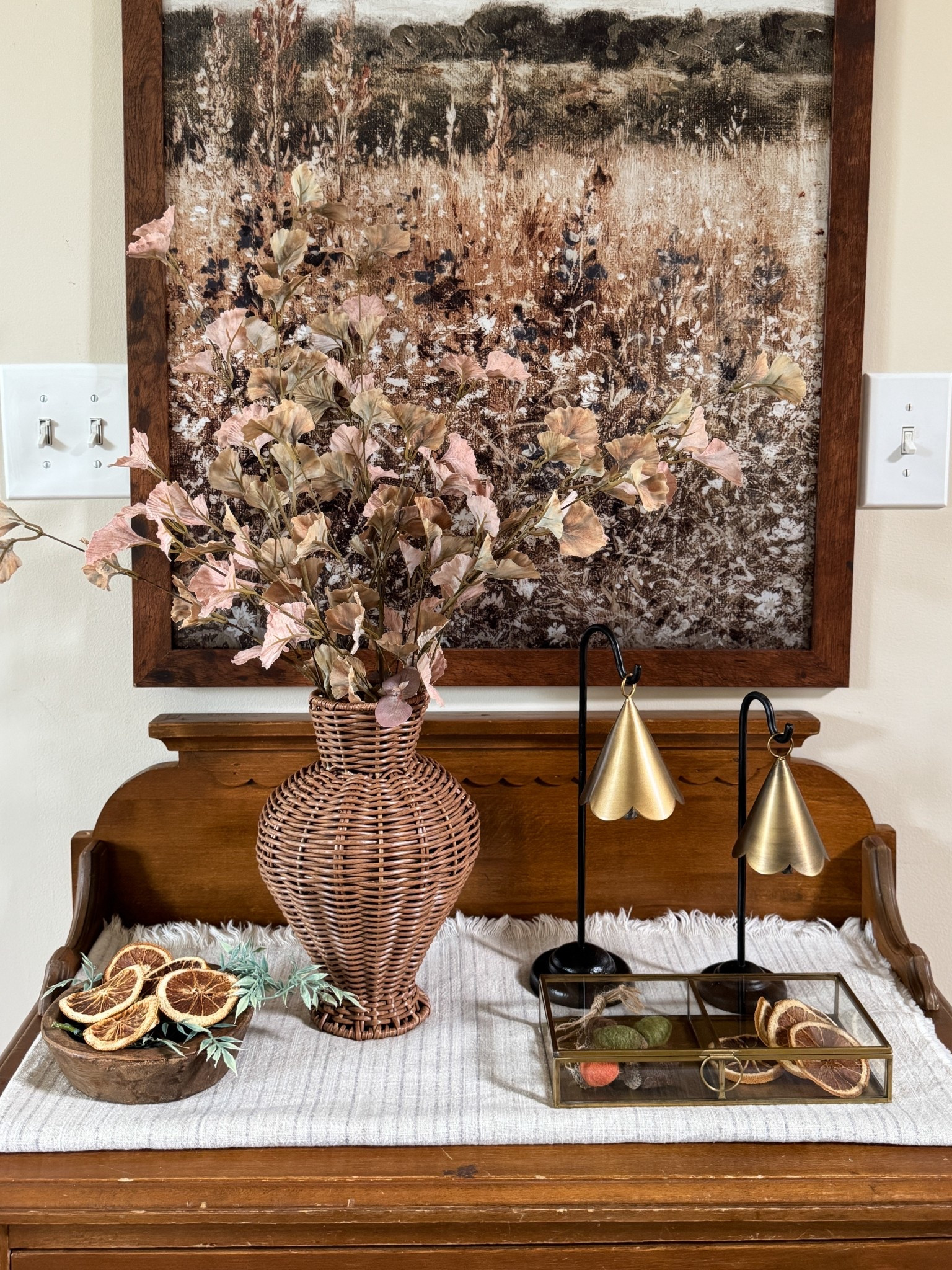 Rope detail glass antique box; standing scalloped brass bells, similar wall print, warm woven vase and brown leaf stems, bag of dried oranges  

#LTKFindsUnder50 #LTKHome