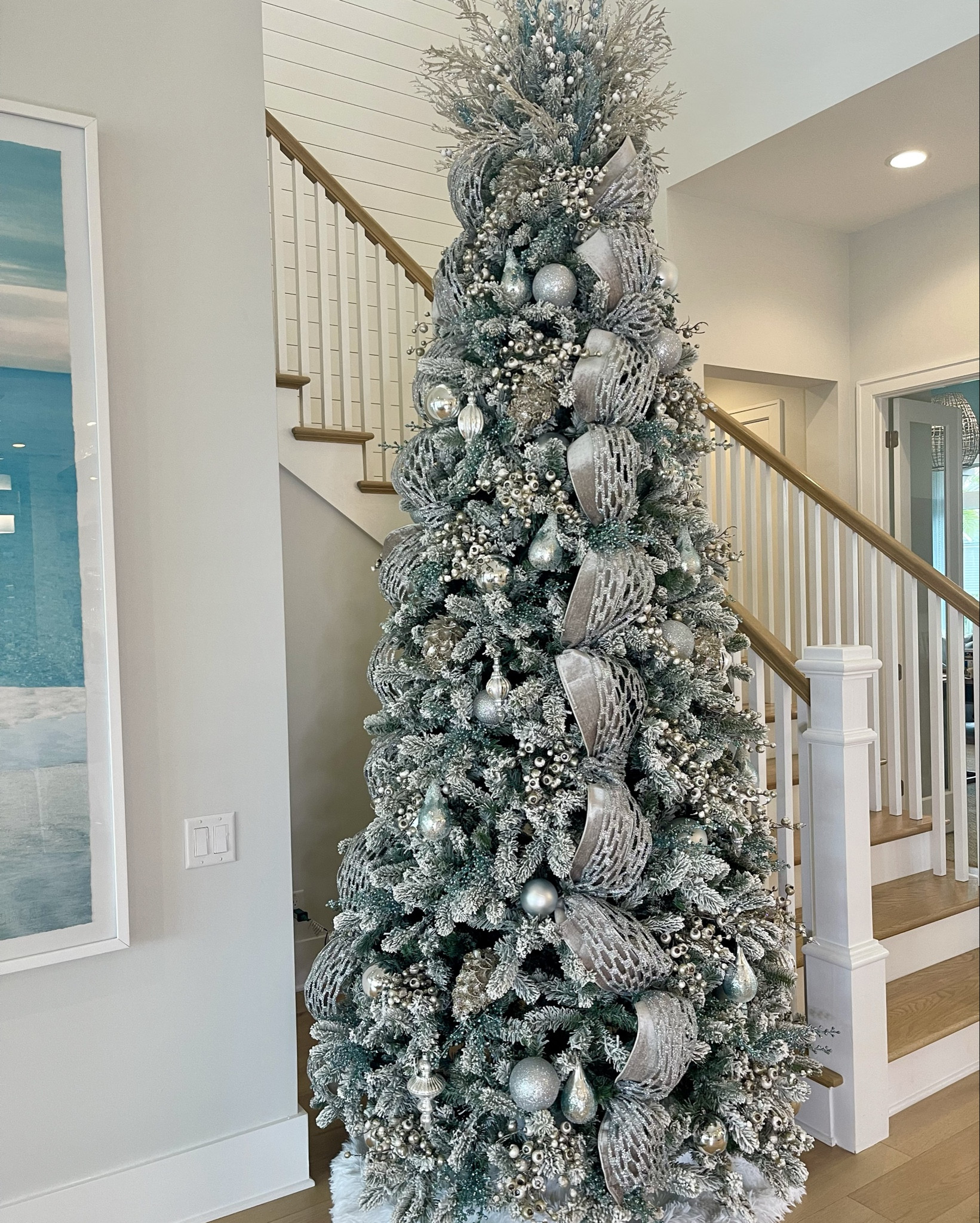 This gorgeous flocked tree is 10 feet tall and it’s considered slim. This company is my go to for Christmas trees of all kinds, especially flocked trees.

I designed this tree to match the gorgeous modern decor in this coastal home. I used silver, champagne, white and light blue throughout this design. It’s a showstopper in person. 

I also got creative and purchased a blanket for a tree skirt. It’s much more full than a normal tree skirt and it’s much less expensive.
#ltkchristmas #christmastreeideas #flockedchristmastree #christmasdecor #platinumchristmas #christmastreedesign
#LTKhome #LTKstyletip

#LTKSeasonal