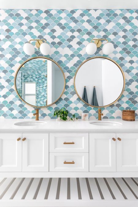 This primary bath includes a multi-colored scalloped backsplash tile, infusing the space with vibrancy and character.  The white shaker-style vanity exudes timeless elegance while providing ample storage. The warm tones of the brass-framed round mirrors add sophistication. #primarybathdesign #primarybath #tranquilbath #luxurybath #bathroomdesign #moroccaninspiredbath #moroccanthemebath 

#LTKHome