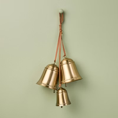 Three brass-colored bells hanging from a leather strap