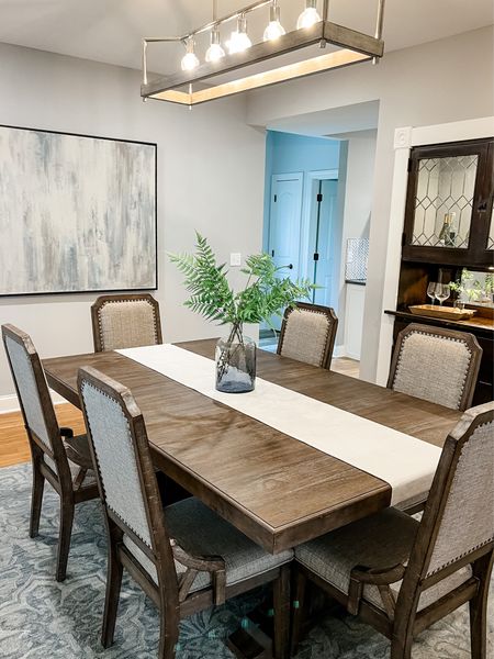 A large dining room with a beautiful dining table! The fabric and wood chairs complement the wood table and brings softness to the space. We added a a subtle pop of color with the stems and vase.

#LTKfamily #LTKhome #LTKstyletip