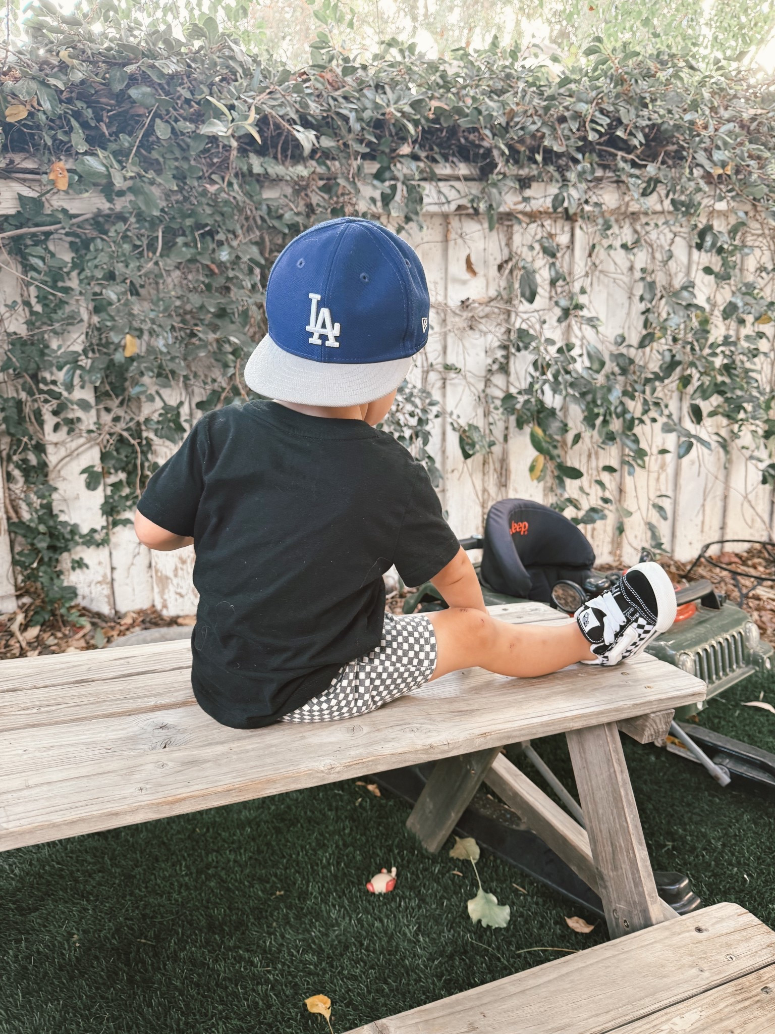 Little man, big style ⚾💙 Repping our favorite team and living his best backyard life 🧢✨
Shop his look : comfy, cool, and toddler-proof 😎
#ToddlerStyle #BoyMomLife #LTKKids #ToddlerOOTD #BaseballBaby #LAStyle #ToddlerFashion #MomFinds #LTKMom #BackyardDays #LTKSaleAlert
	•	LA Dodgers cap 🧢-Amazon
	•	Checkered shorts 🩳-Target 
	•	Black tee 👕-Target
	•	Vans-style sneakers 👟-Amazon 

#LTKmomlife #LTKBaby #LTKKids