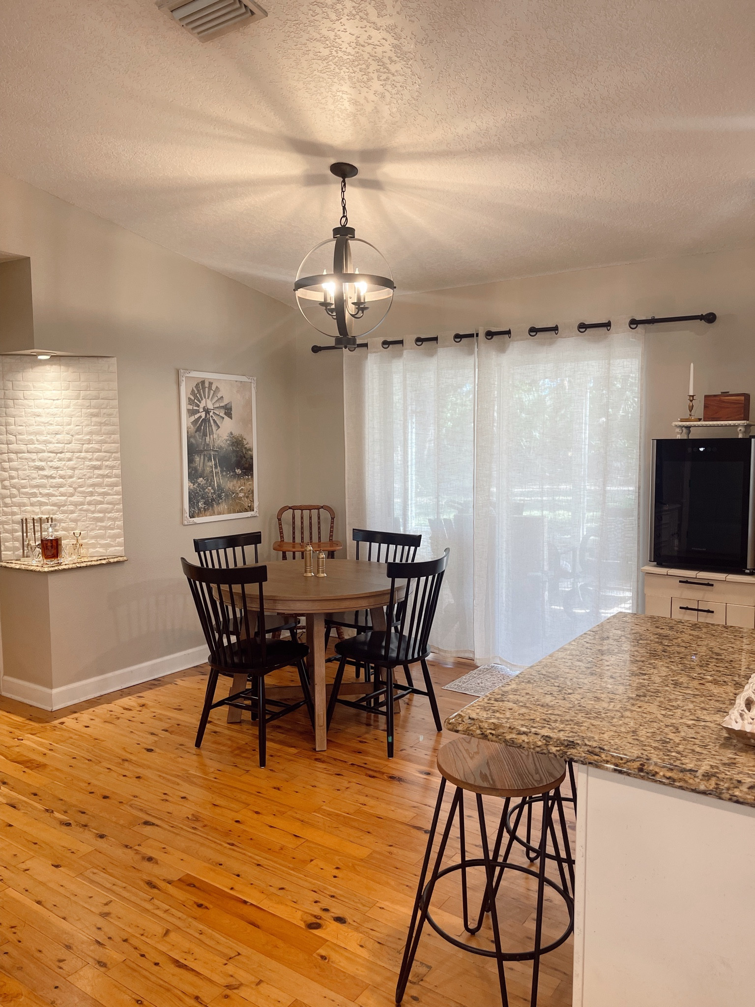 Our new dining room area and table! We love this round natural wood table with an extendable leaf and black chairs from Amazon! It looks very similar to the pottery barn table and we love the quality. Also linked our round barstools, affordable burlap curtains and curtain rods, peel and stick white stone we used on our nooks, the gold bar tools from Target, the cowboy whiskey decanter from Etsy, and similar black antique styled light fixtures like ours here! All the farm cottage style with antique charm

#LTKHome #LTKFamily