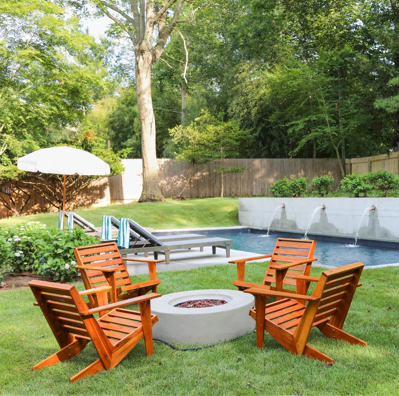 Backyard setup with Adirondack chairs, a fire pit, in-pool loungers, and water feature along the pool wall. Added a striped umbrella, and lounge chairs throughout the outdoor space. Linking exact and similar pieces here.

#LTKHome #LTKSaleAlert