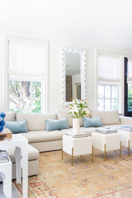 Light and airy living room design with large corner sectional, cream ottoman stools, white wavy mirror, and blue accent decor 

#LTKfindsunder100 #LTKhome #LTKstyletip