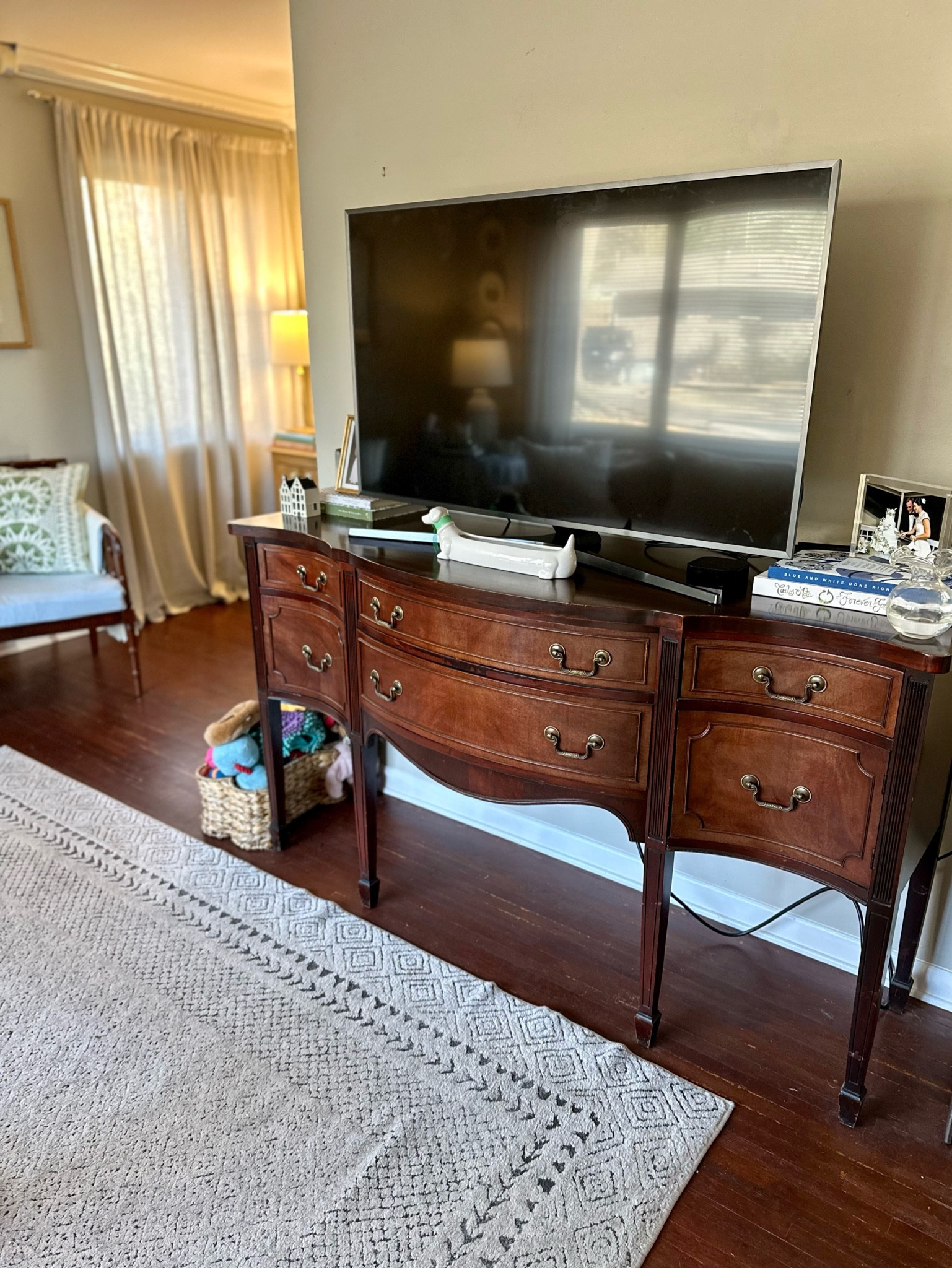 We’re lucky to be able to borrow this unused sideboard from Hunter’s parents storage unit to use as our media console. I love traditional style furniture and think this piece adds warmth and elegance to our space! I’ve linked some similar sideboards that I found online as well as similar chairs to the ones I found at an antique store, but I highly recommend searching Facebook marketplace and your local antique stores! To make the tv a little less of a focal point, I added book stacks to either side and accessorized with vases and frames! 

Our living room so far feels pretty finished, but there are still some updates I’d like to make! Here’s a look at how it looks now to give you an idea of the space we’re working with and the different vignettes set up in the room!

First house, living room, blue and green decor, southern traditional, antique furniture, smaximalist, southern maximalism, affordable home decor, interior design hack, cane furniture, faux bamboo furniture, ikea sofa, skirted table

#LTKfindsunder100 #LTKhome