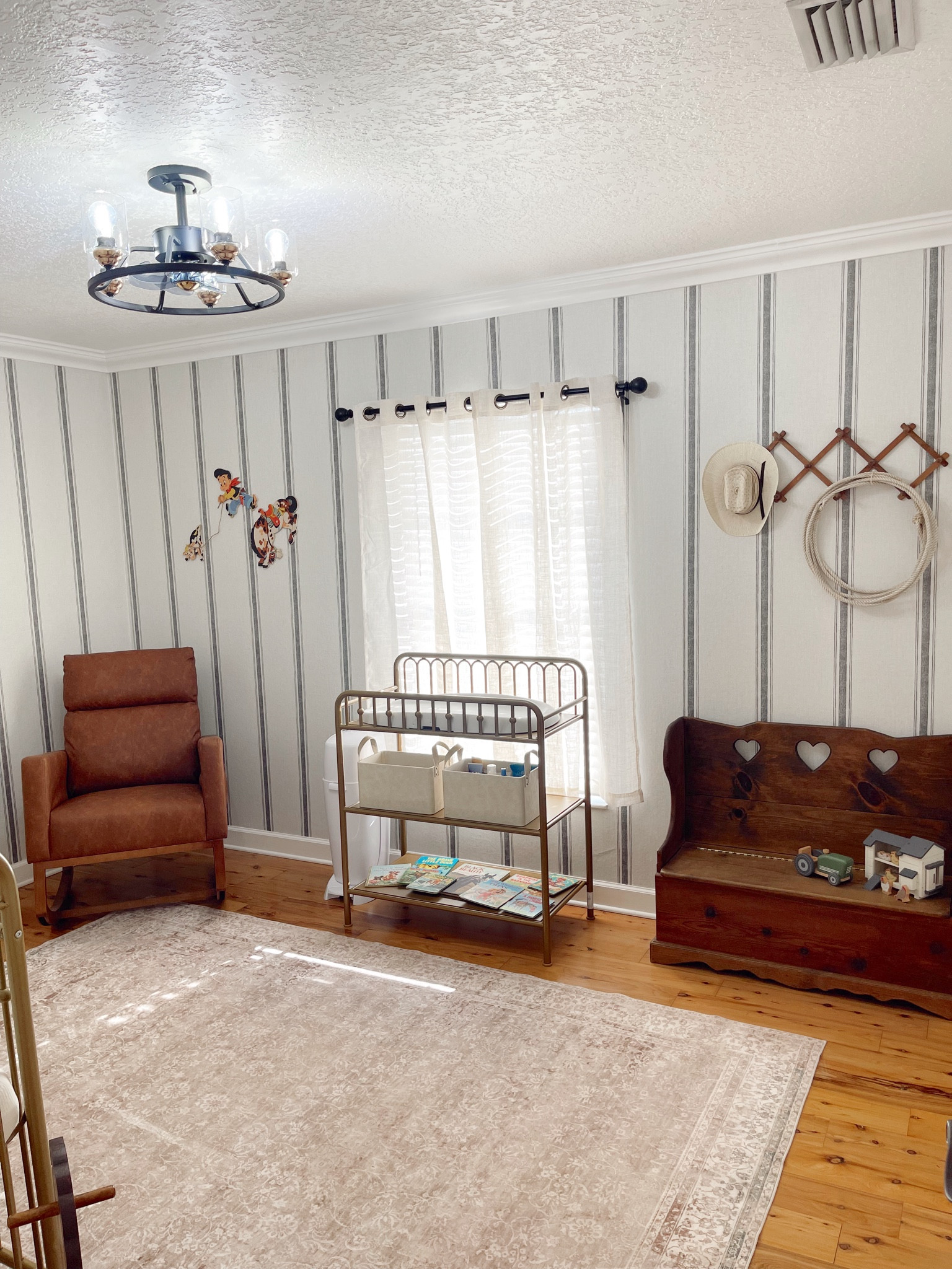 Western, vintage cowboy nursery for baby boy! Striped peel and stick wallpaper is from Amazon and was super easy to apply as well as damage free to the walls! The cream colored light filtering curtains and black curtain rods, as well as the leather rocking chair are from Amazon as well and super affordable. The gold antique looking changing table that matches the crib is available at Walmart and Amazon both. The black light fixture or chandelier with a built in fan, is from Amazon and was a budget friendly option for lighting with great function and comes with a remote for the fan & light settings which is super convenient. This large cream colored rug is also from Amazon and SO soft! It was hard finding an affordable area rug I loved but I finally found this one and it’s been the best! The wooden antique toy box is a family heirloom but the wooden farm toys are from target with the magnolia home line. I linked the toddler cowboy hat, antique wood accordion style wall hooks, and vintage cowboy wall art as well!

#LTKHome #LTKFindsUnder100 #LTKBaby