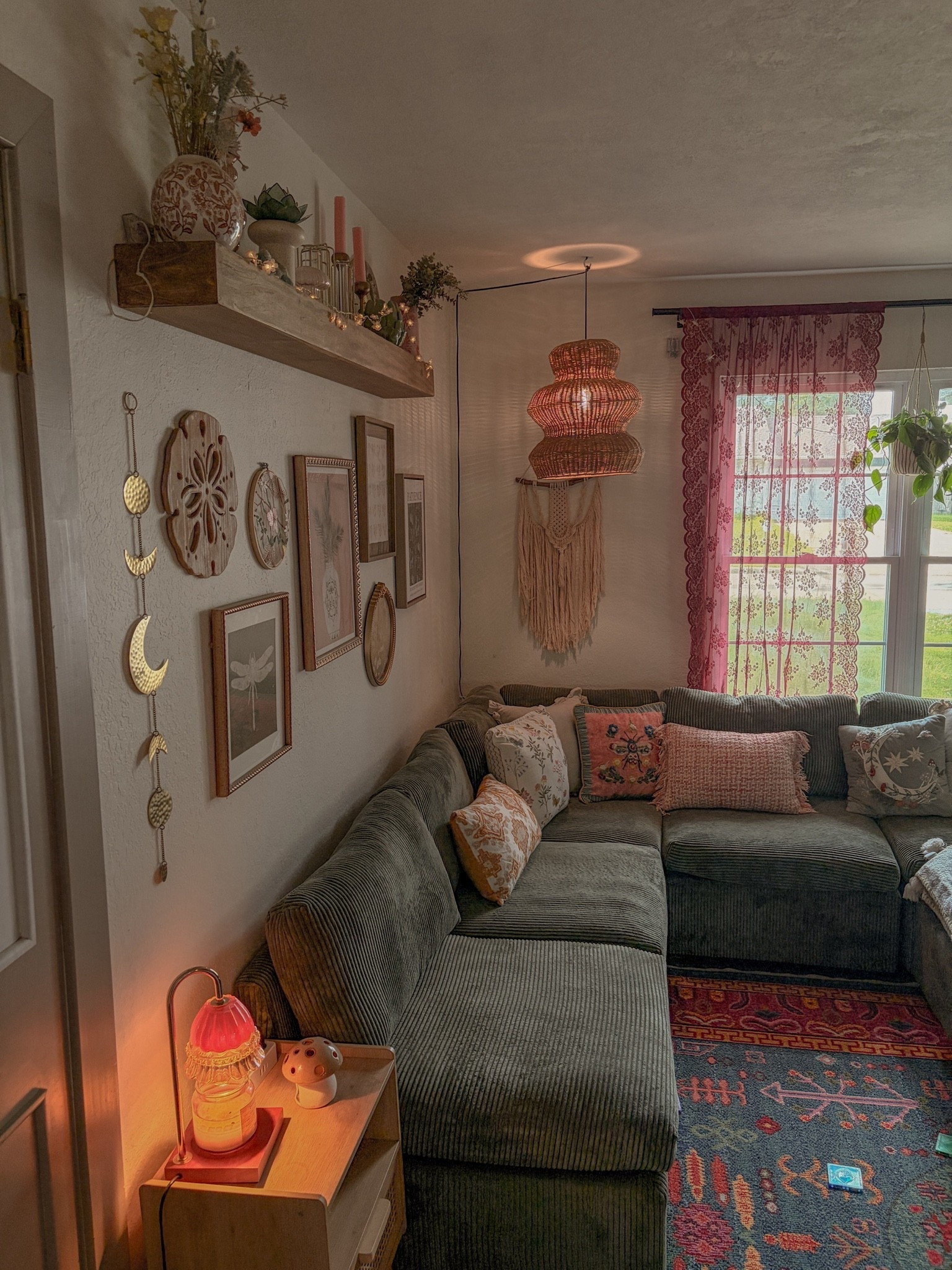 sunlight streaming through pink lace curtains and disco ball accents creates colorful reflections throughout this cozy bohemian living room designed for dreamers and plant lovers