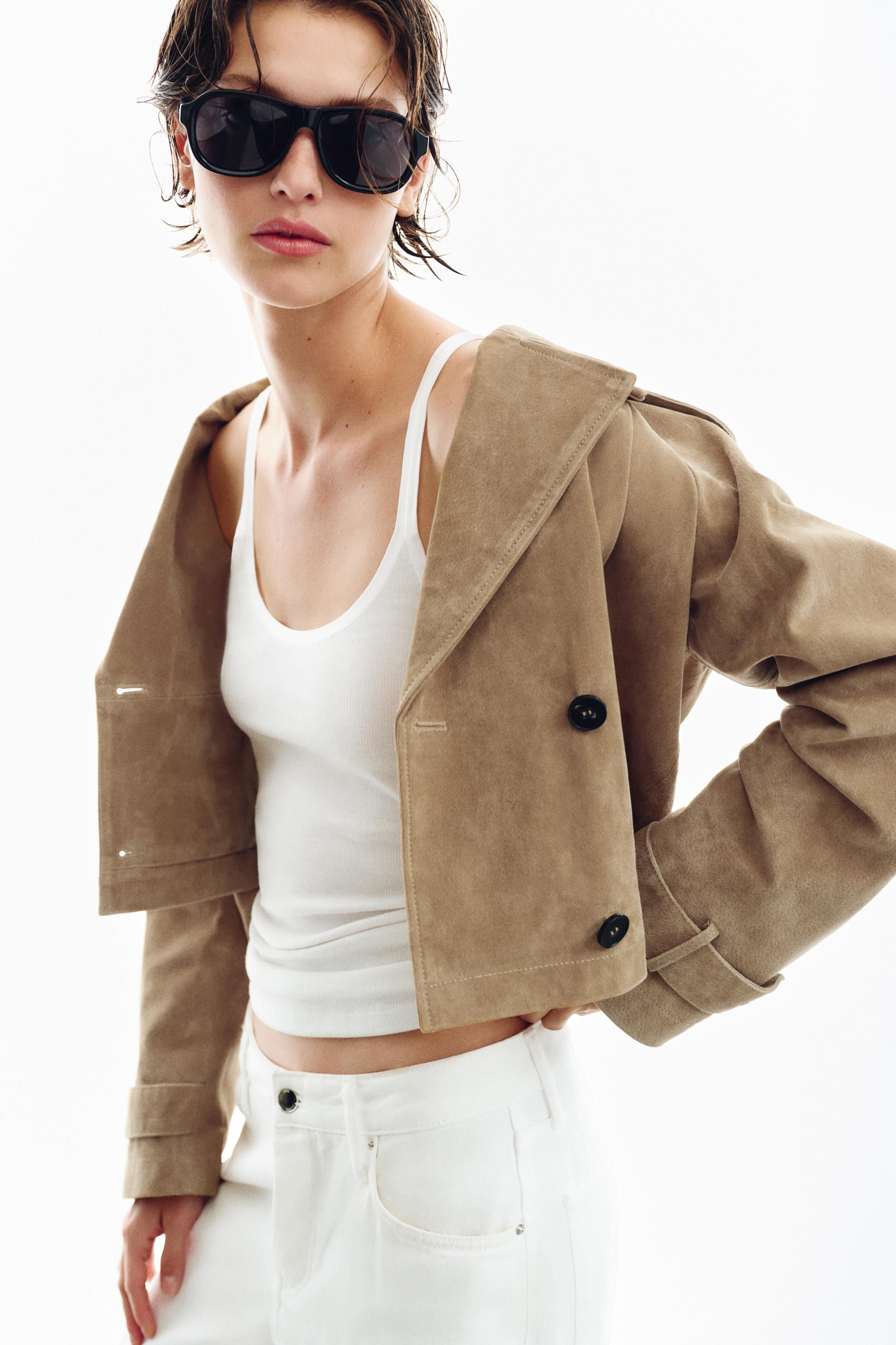 Short trench coat crafted from 100% leather main fabric. Lapel collar and long sleeves with tab a... | Zara US
