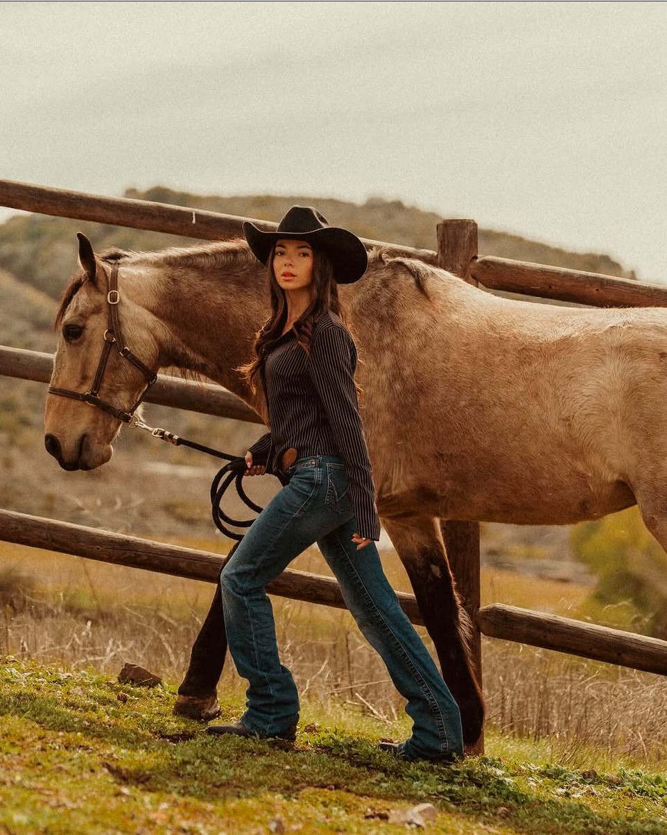 Ranch days are my favorite 🐎 I’m wearing one of my go-to rodeo looks: a black pinstripe button-up tucked into my favorite high-rise bootcut jeans. These jeans fit true to size (I’m wearing a 25 for reference) and are the perfect length to wear over boots without dragging. The shirt is fitted but comfortable—I sized up one for a more relaxed look, and it still tucks in nicely under a belt.

These black leather cowboy boots are broken-in just right and give me all-day comfort whether I’m riding, walking the pasture, or spending hours at a rodeo. I topped the look with a classic black felt hat—timeless and versatile for any western outfit.

If you’ve been searching for western outfit inspiration, rodeo fashion ideas, or ranch-ready looks, this is such an easy combination to recreate. Functional, flattering, and authentic cowgirl style that works for both arena days and casual outings.
