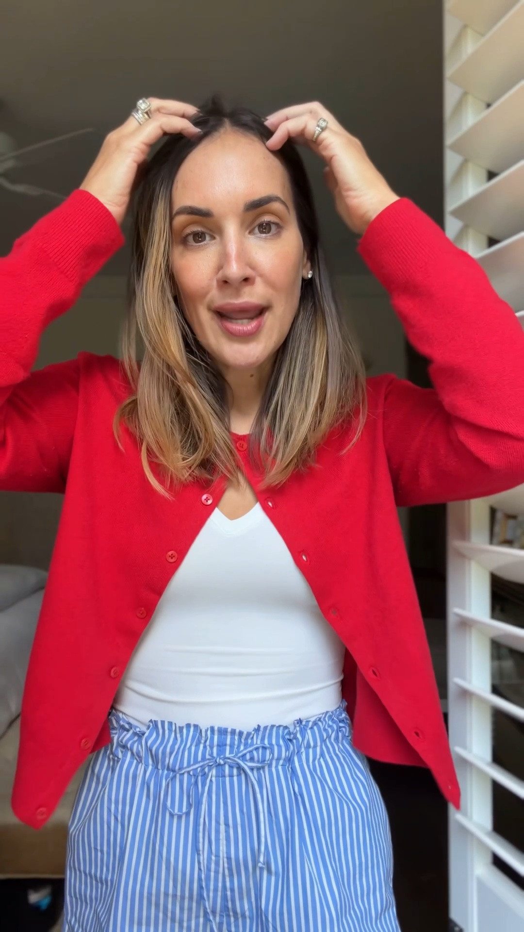 Red cardigan sweater with a white bodysuit and blue pinstriped shorts -