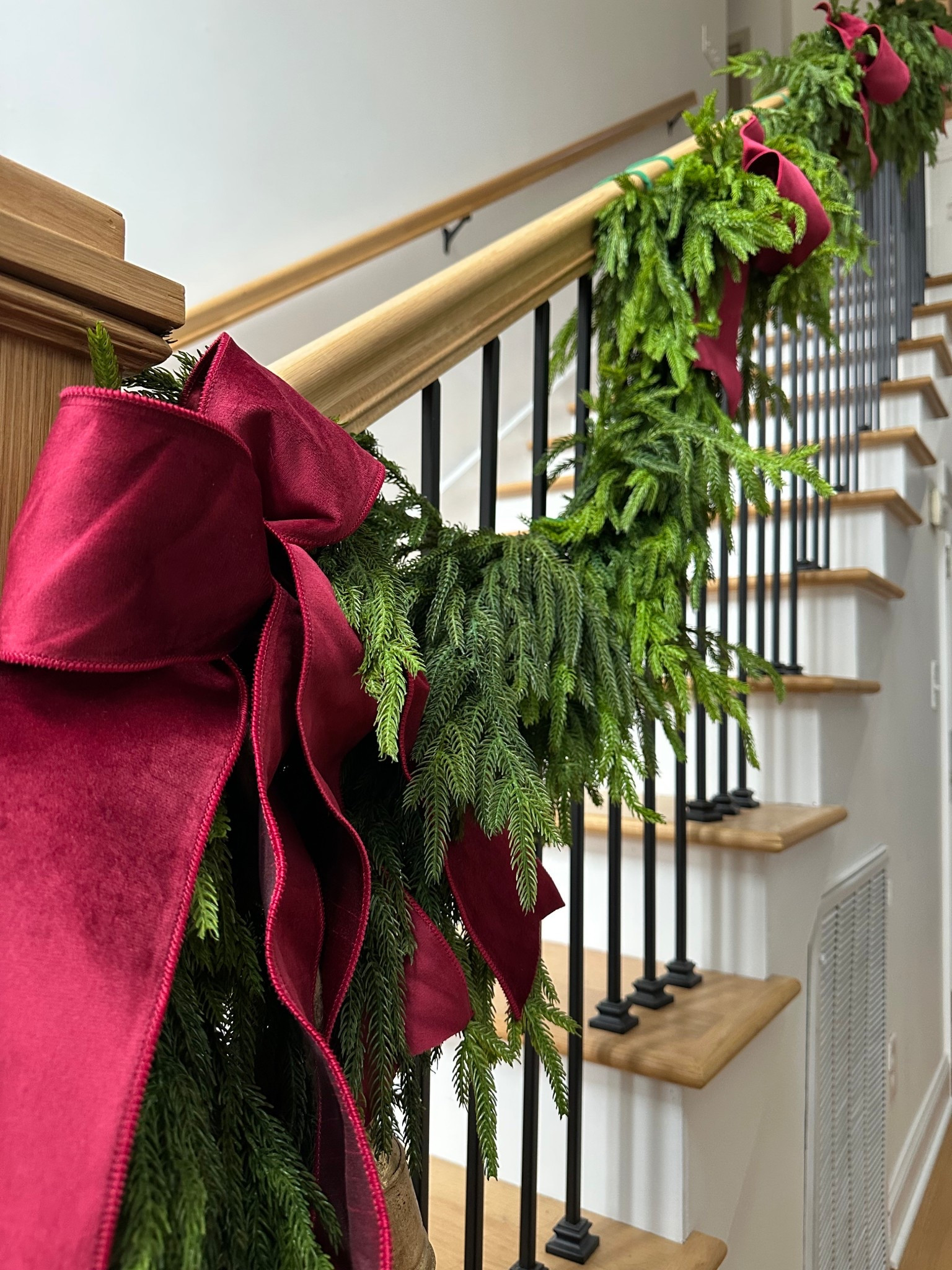 Garland and a thick velvet burgundy ribbon is all you need. I kept the staircase simple this year, layering  Norfolk pine garland and adding a couple extra pieces at the base. What I used: 2 x deluxe Norfolk pine along the entire banister. 2 extra pieces at newel post. Burgundy ribbon twisted into bows and bells at the base. #christmasdecor #garland #holiday 

#LTKSeasonal #LTKHome #LTKHoliday