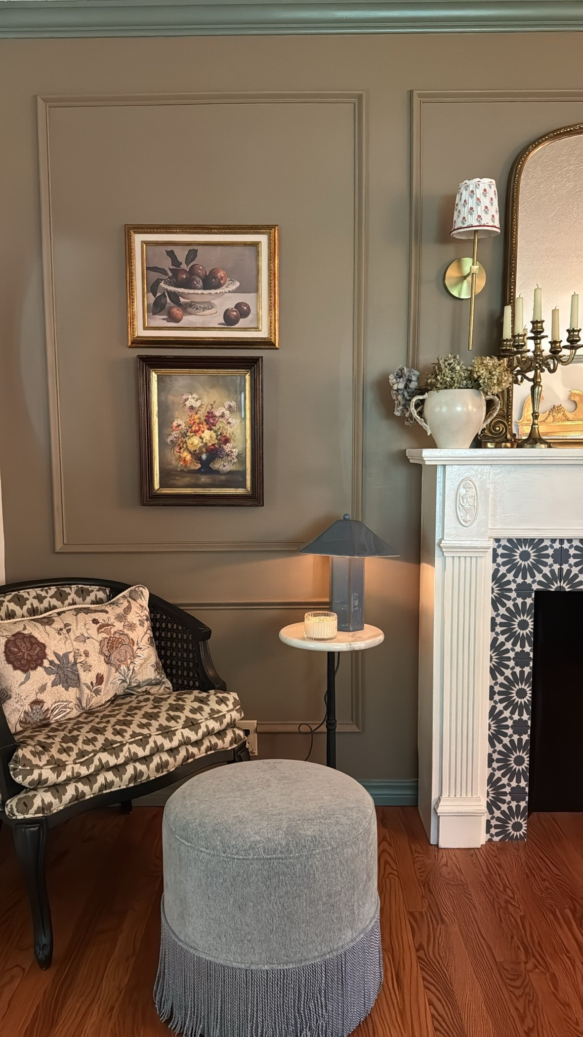 Vintage inspired framed art, floral
Pillow, upholstered ottoman with fringe, ceramic vase, ceramic lamp, ornate gold mirror, pleated chandelier lamp
Shade, gold modern sconce