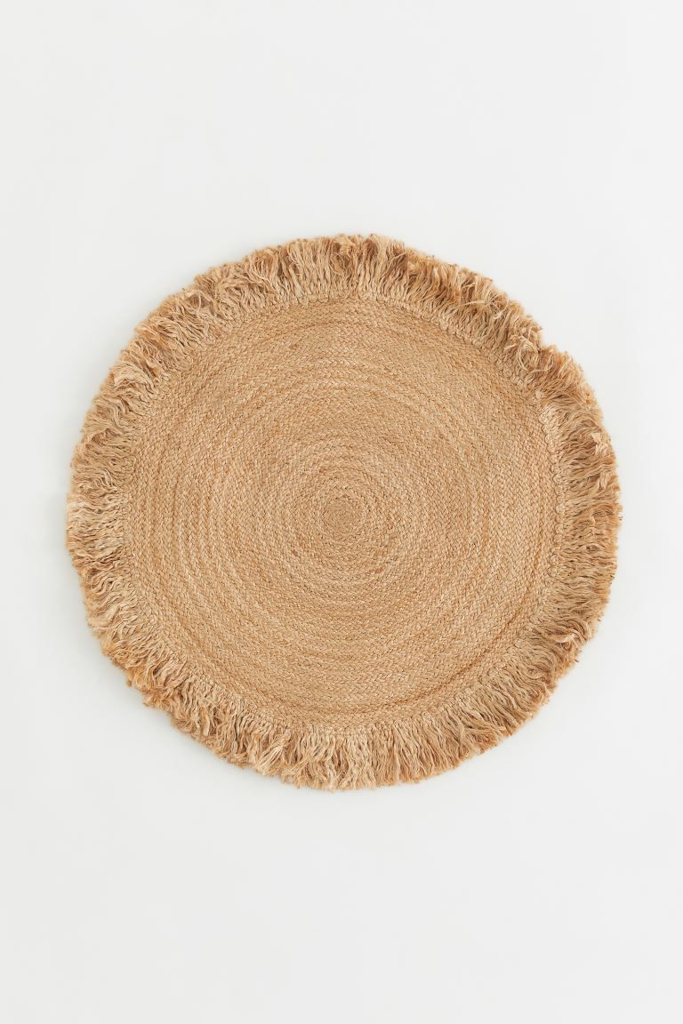 Small, round rug in a jute weave with a frayed raw edge all around. | H&M (US + CA)